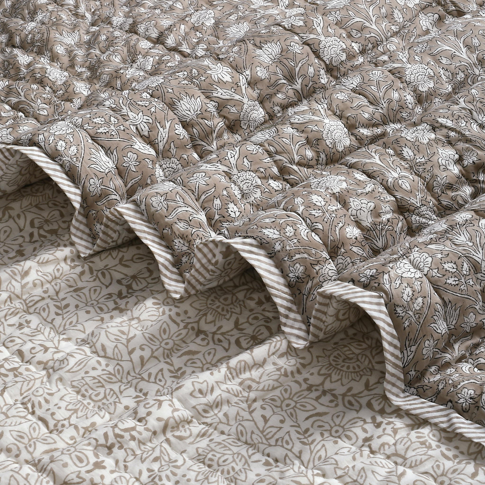 Floral patterned quilt with ruffled edges on a matching fabric background