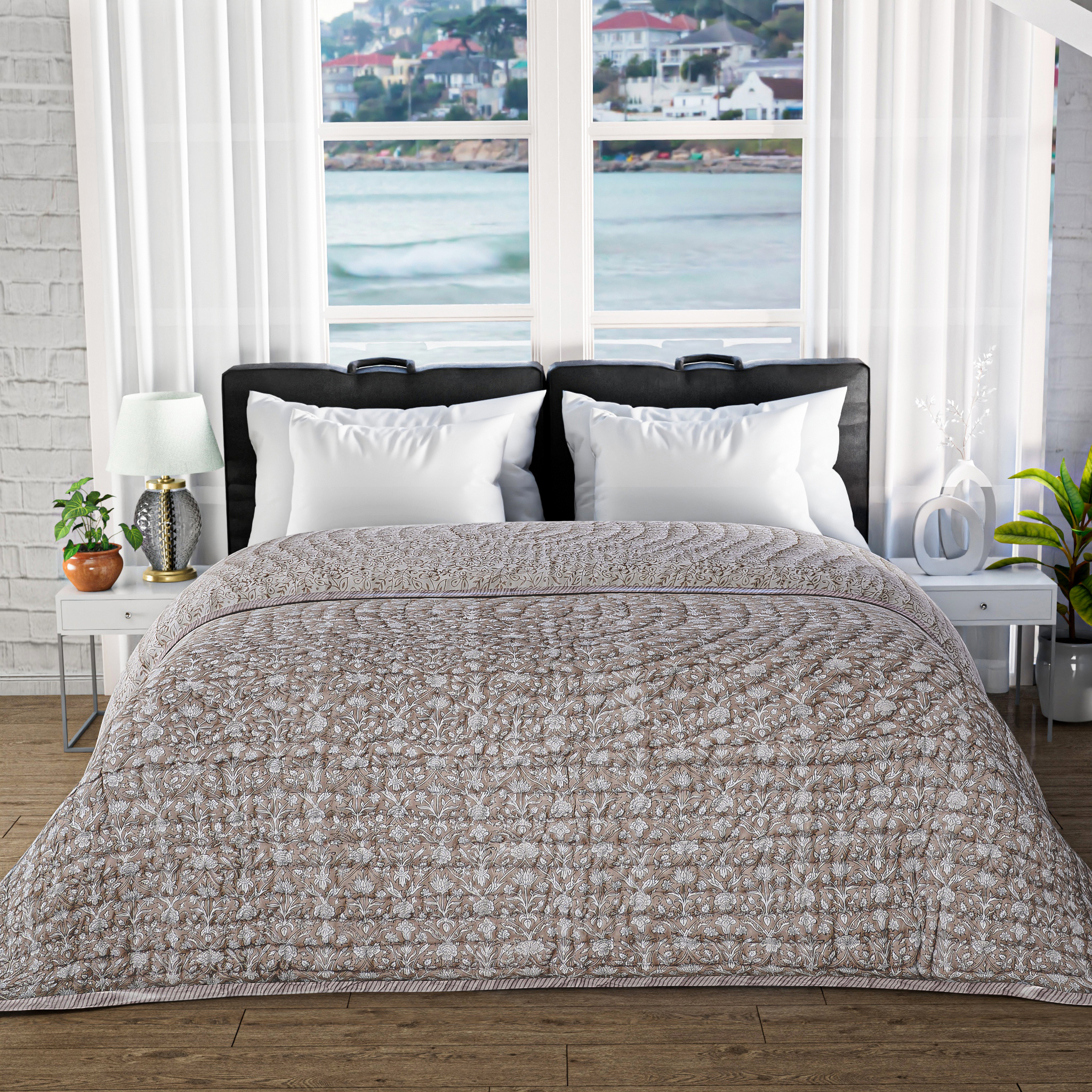 Bed with beige textured comforter in a room with large windows showing a waterfront view.