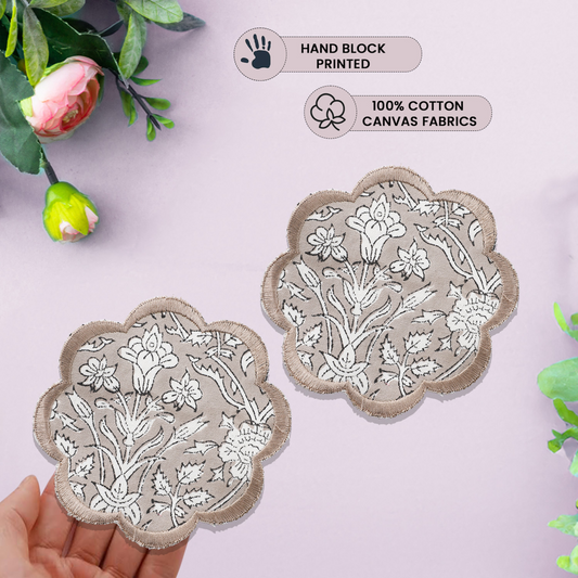 Two floral embroidered patches held by a hand with greenery in the background, labeled as hand block printed and 100% cotton canvas fabrics.
