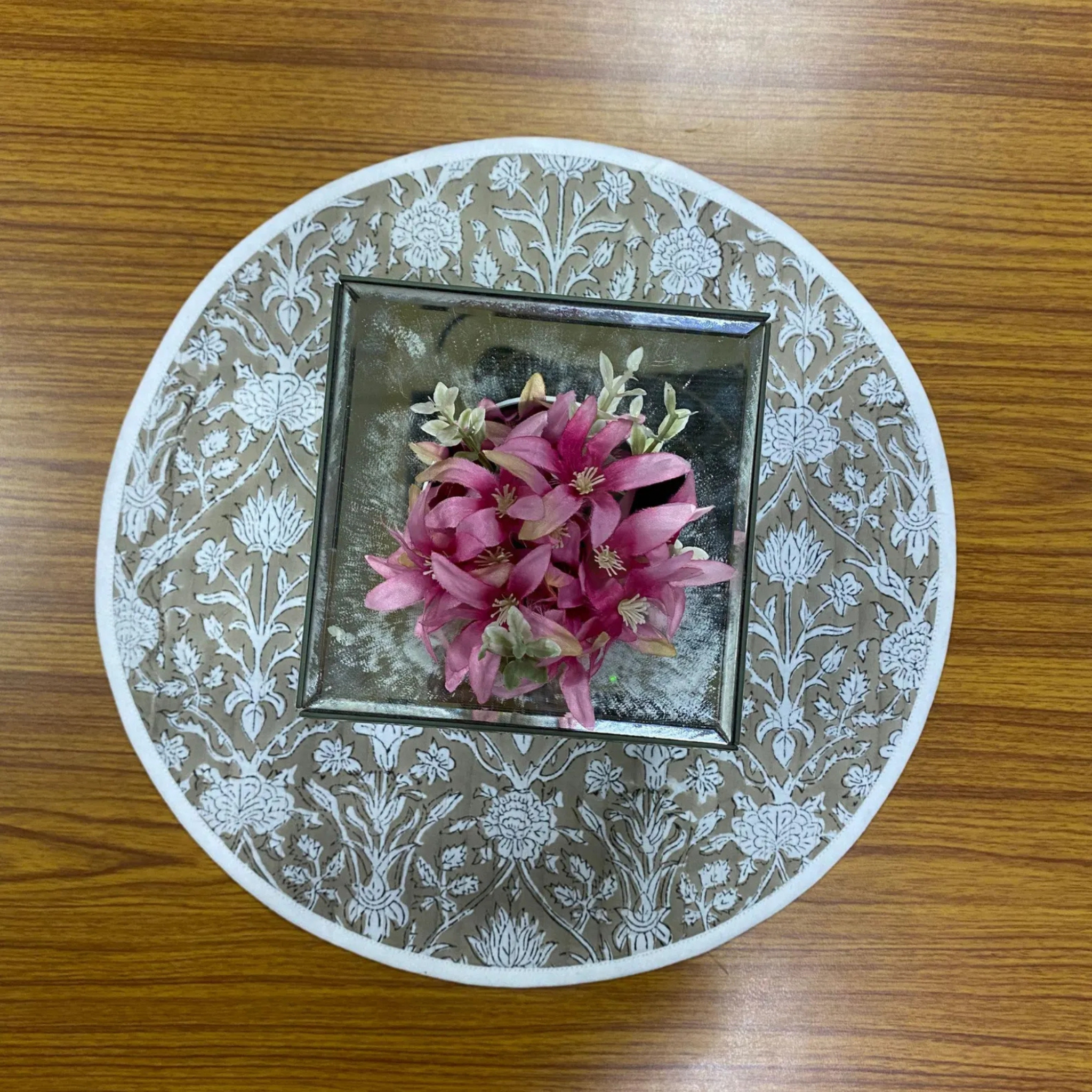 Decorative plate with floral design and pink flowers on a wooden surface