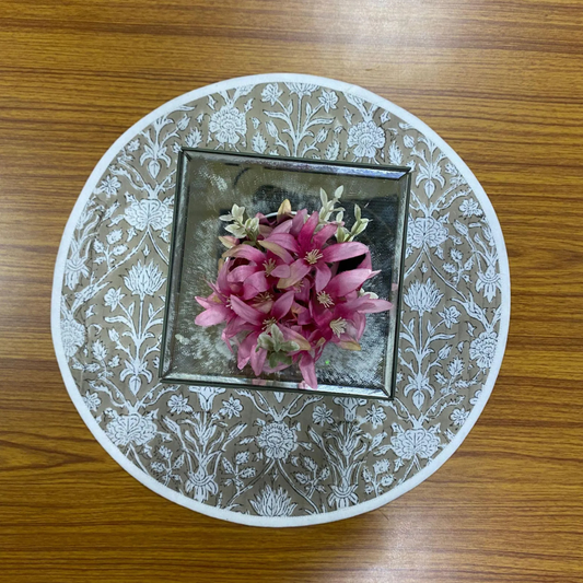 Decorative plate with floral design and pink flowers on a wooden surface