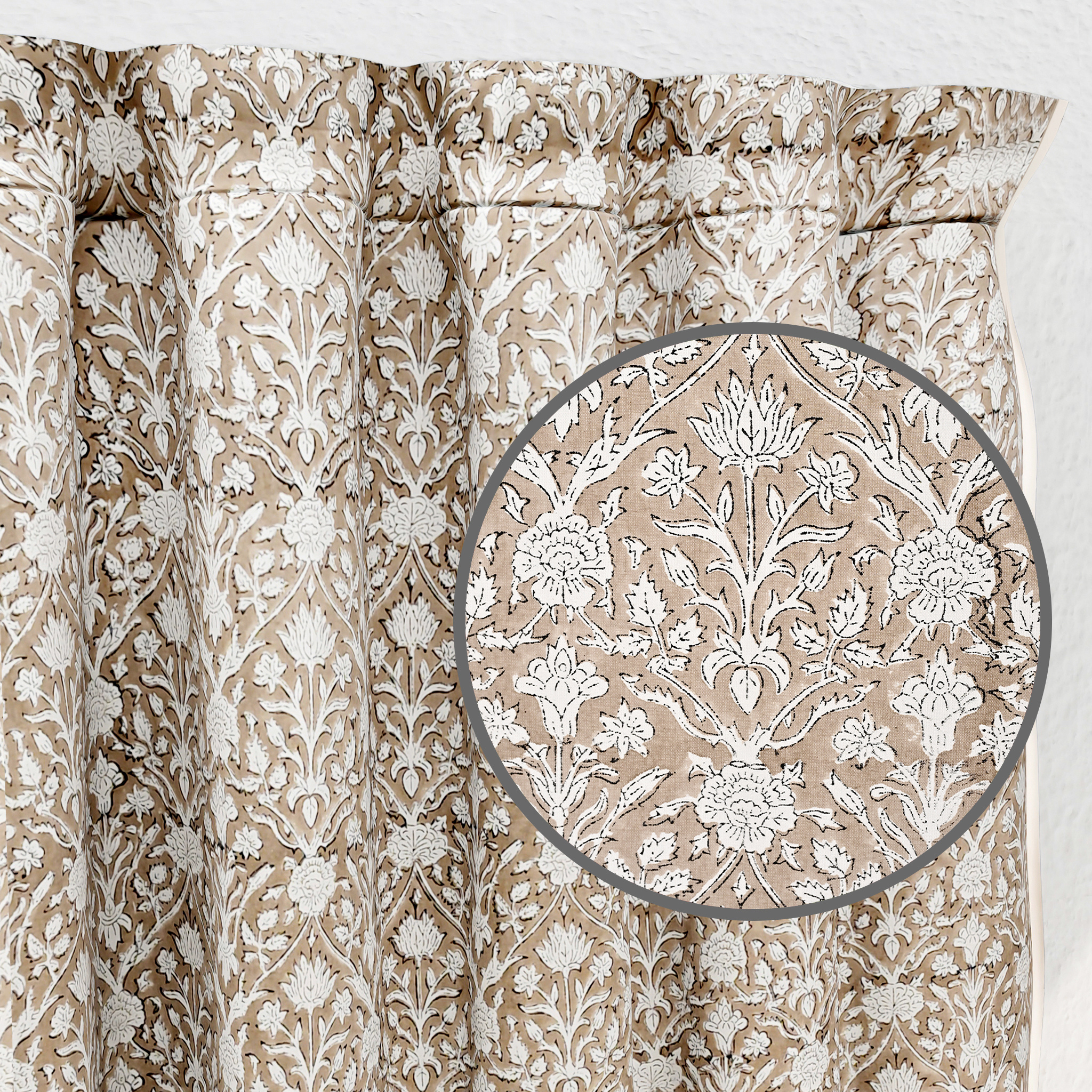 Close-up of beige fabric with intricate white floral pattern on a white background