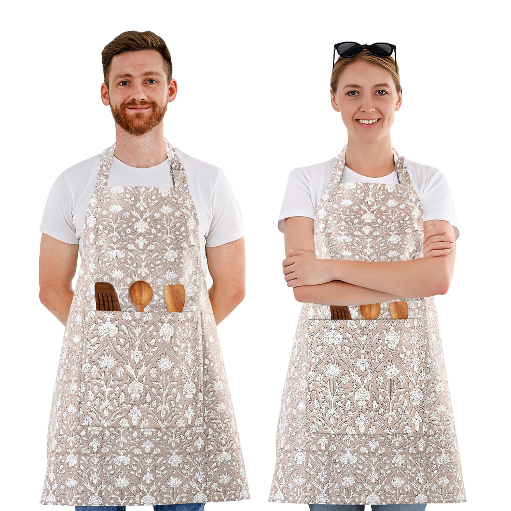 Two people wearing floral aprons with wooden utensils on a white background