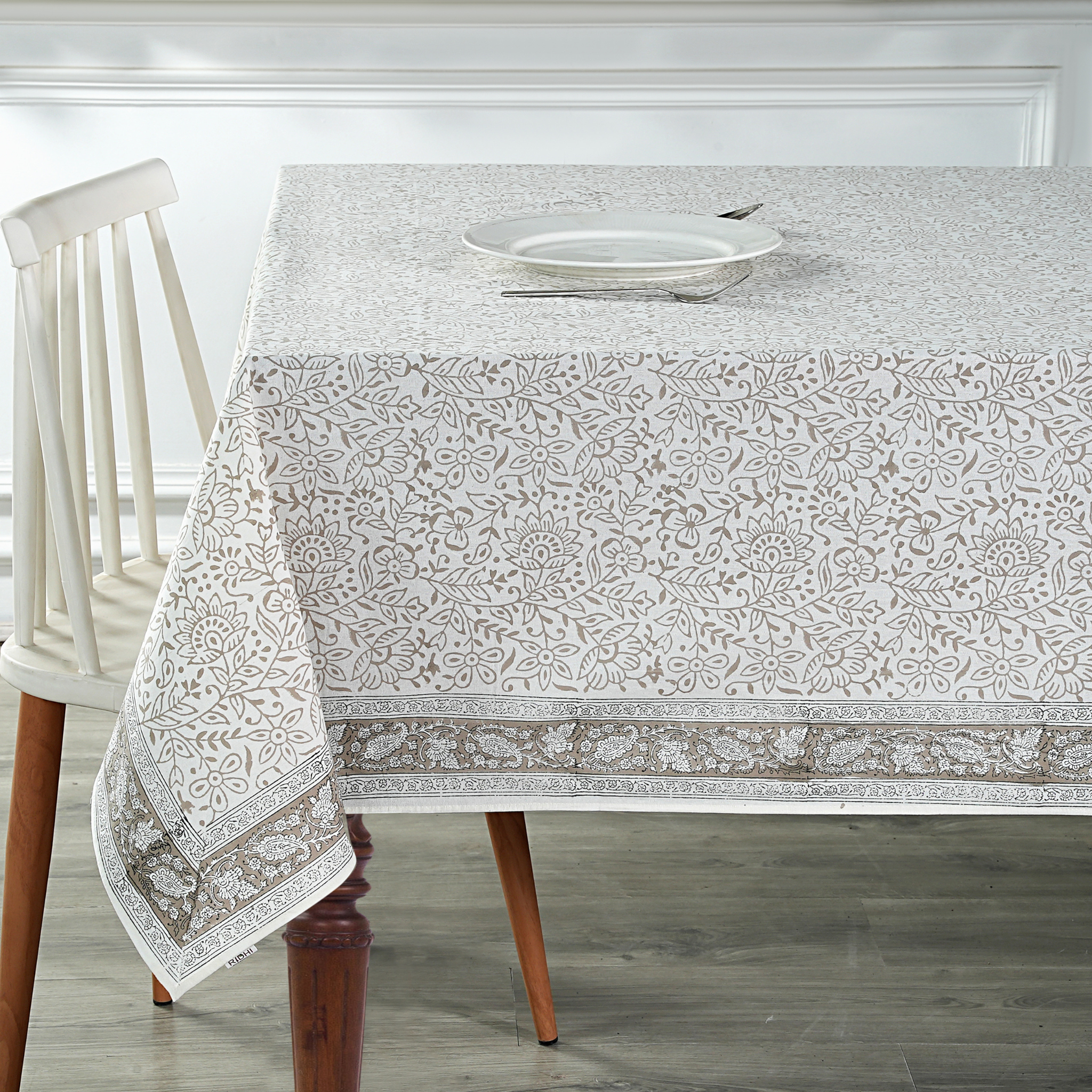 Dining table with a patterned tablecloth and white chair.