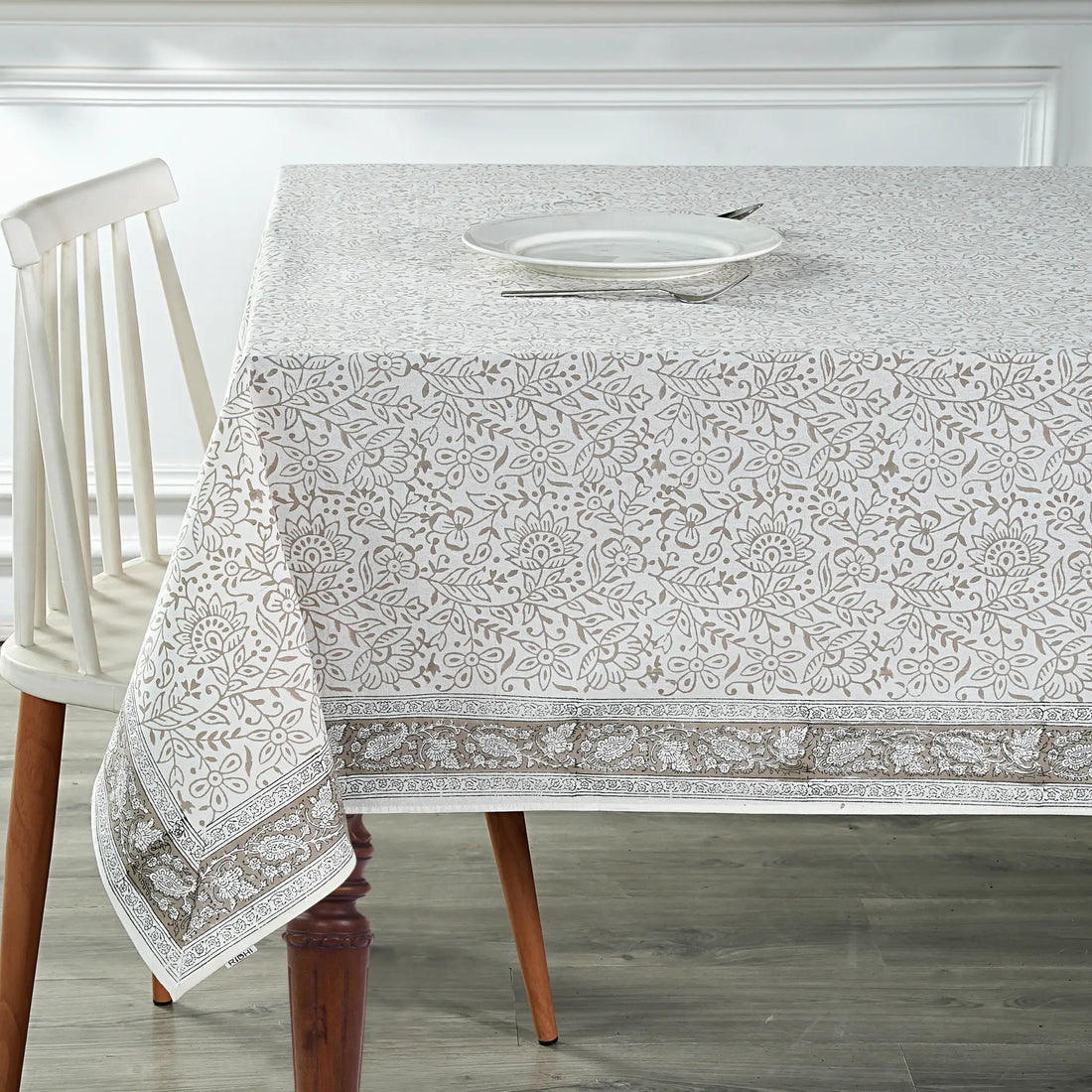Dining table with a patterned tablecloth and white chair.