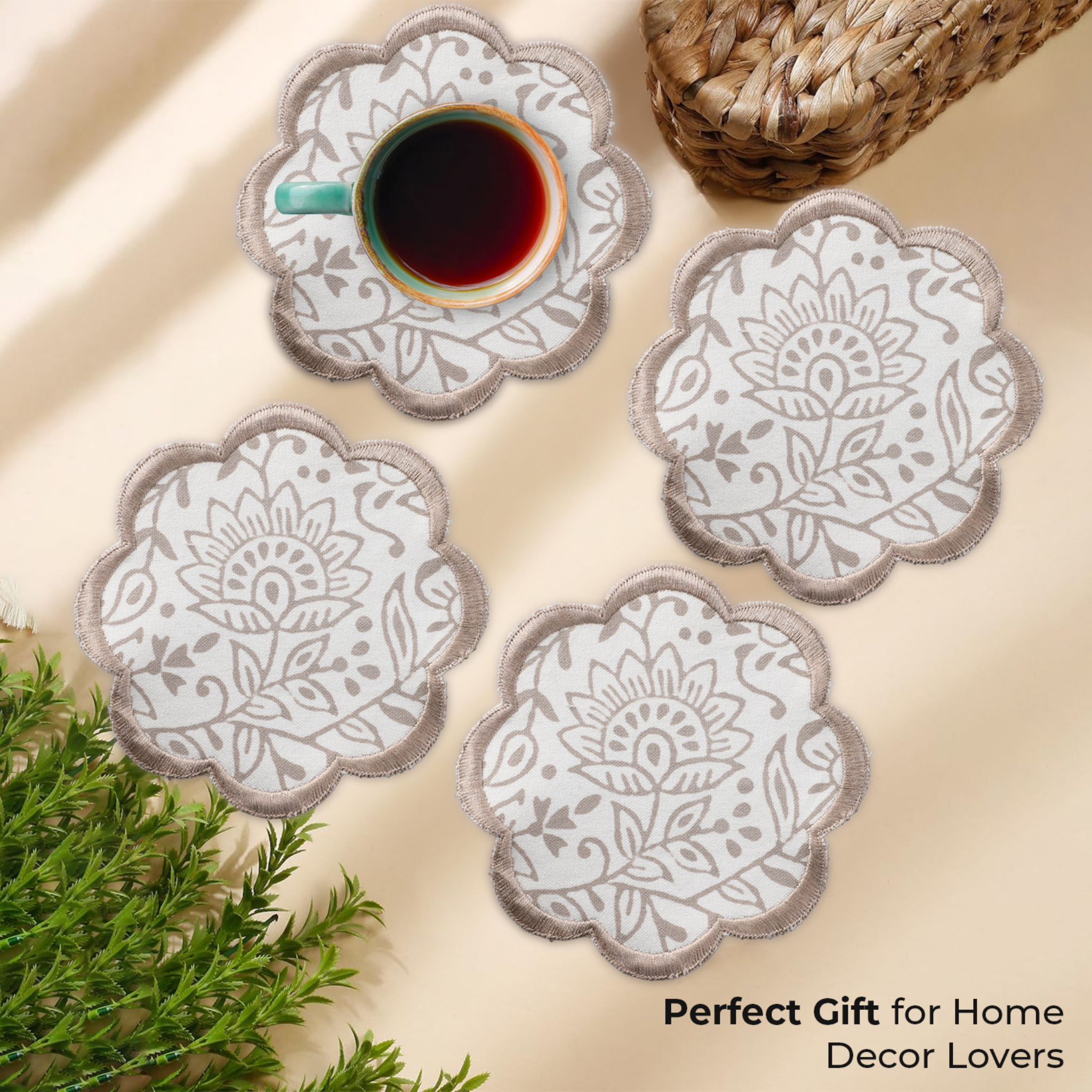 Set of four decorative coasters with floral patterns on a beige surface with a cup of coffee.