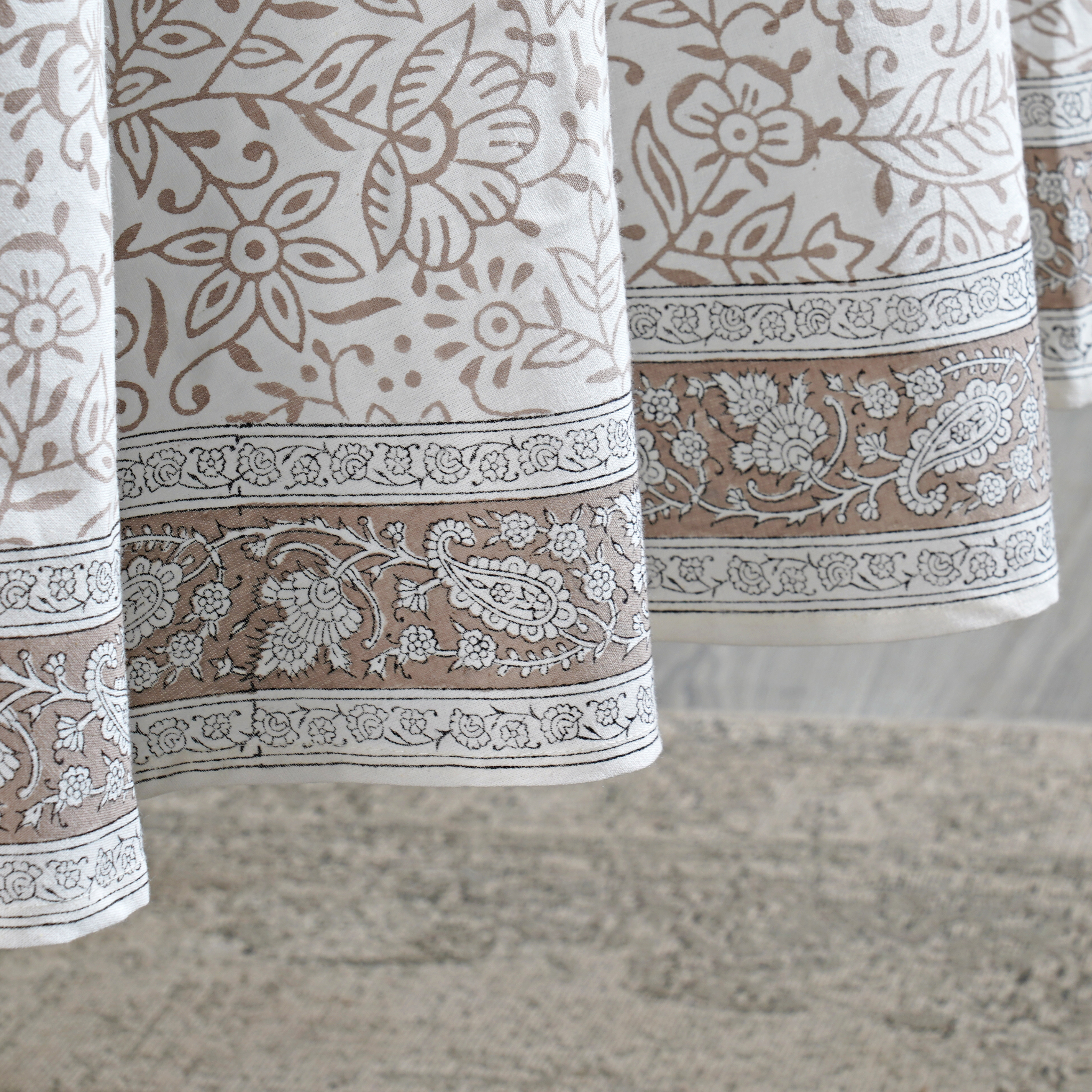 Close-up of patterned fabric with floral and paisley designs on a neutral background