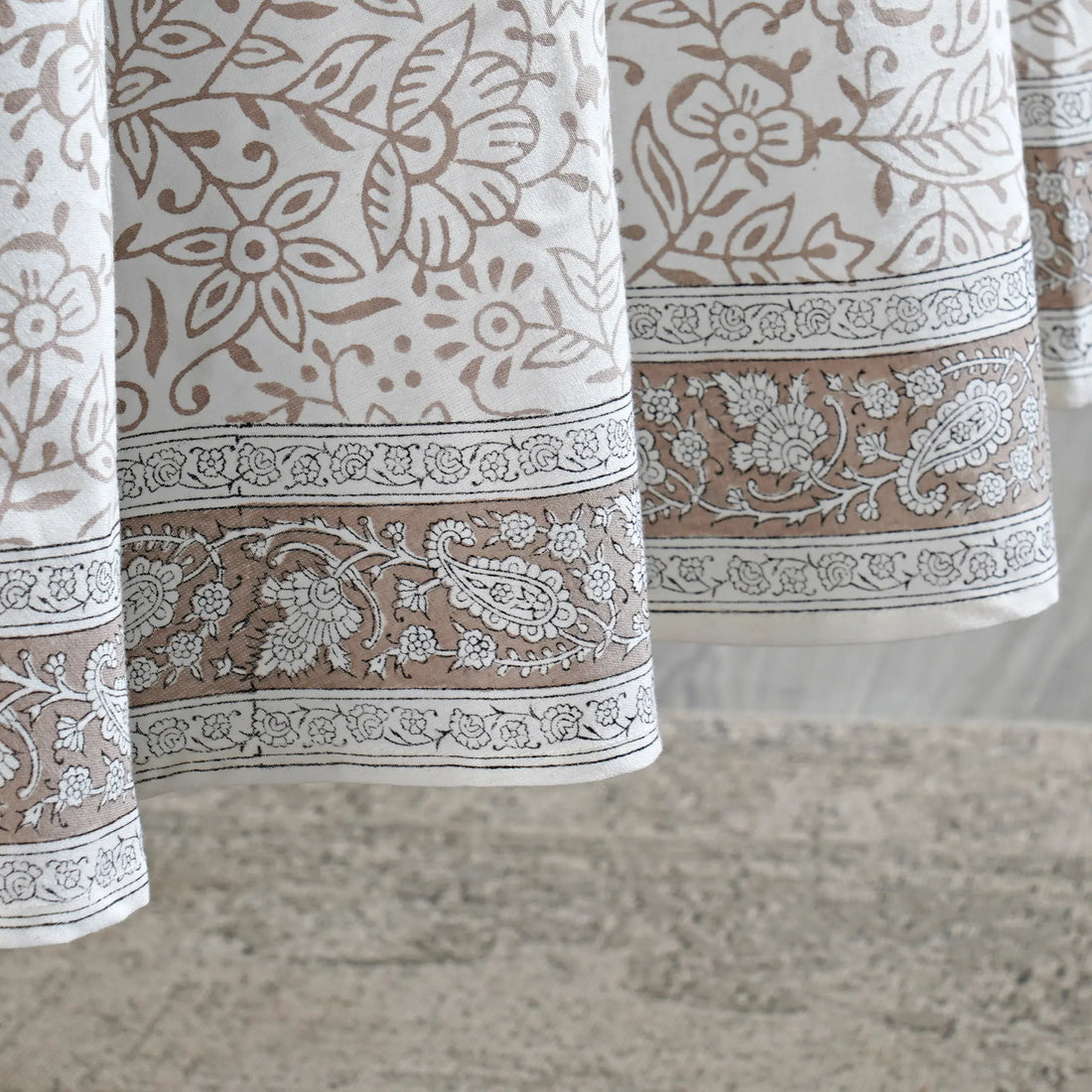 Close-up of patterned fabric with floral and paisley designs on a neutral background