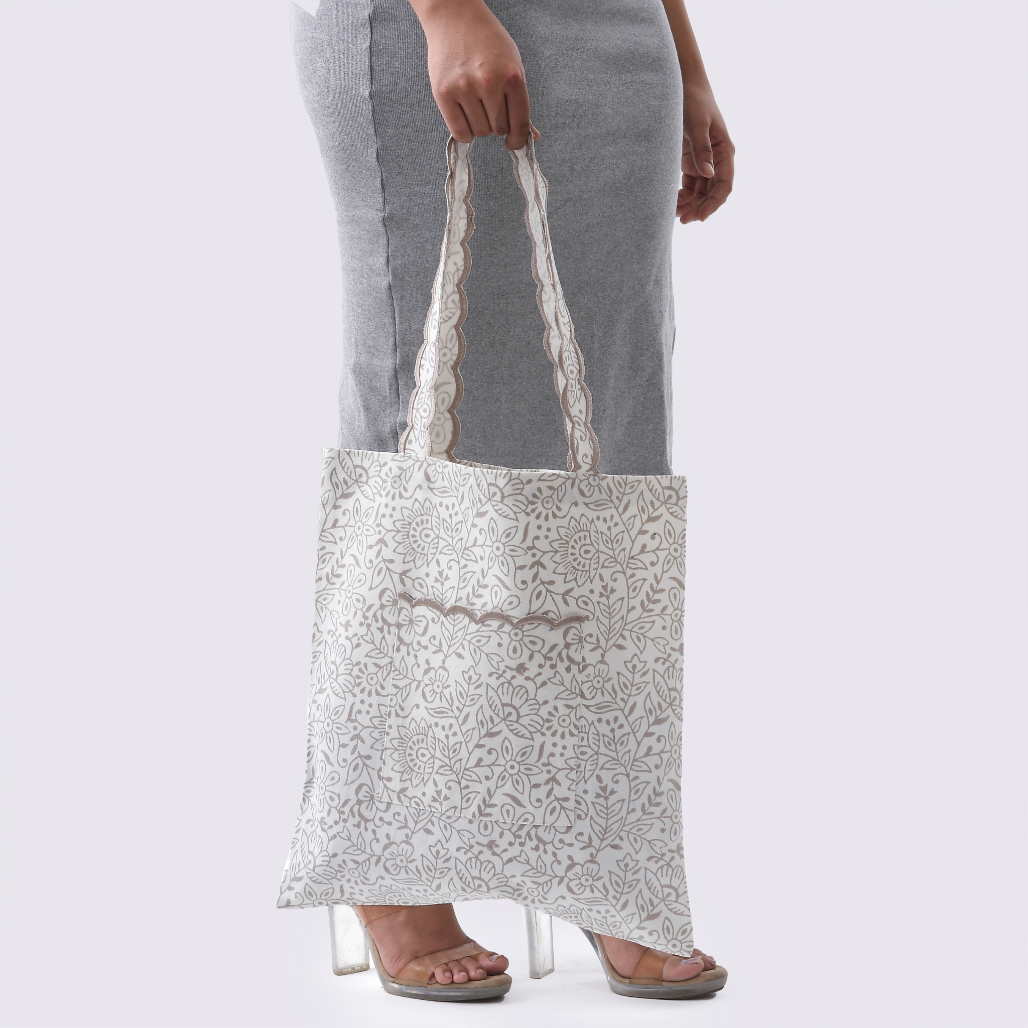 Person holding a patterned tote bag against a plain background