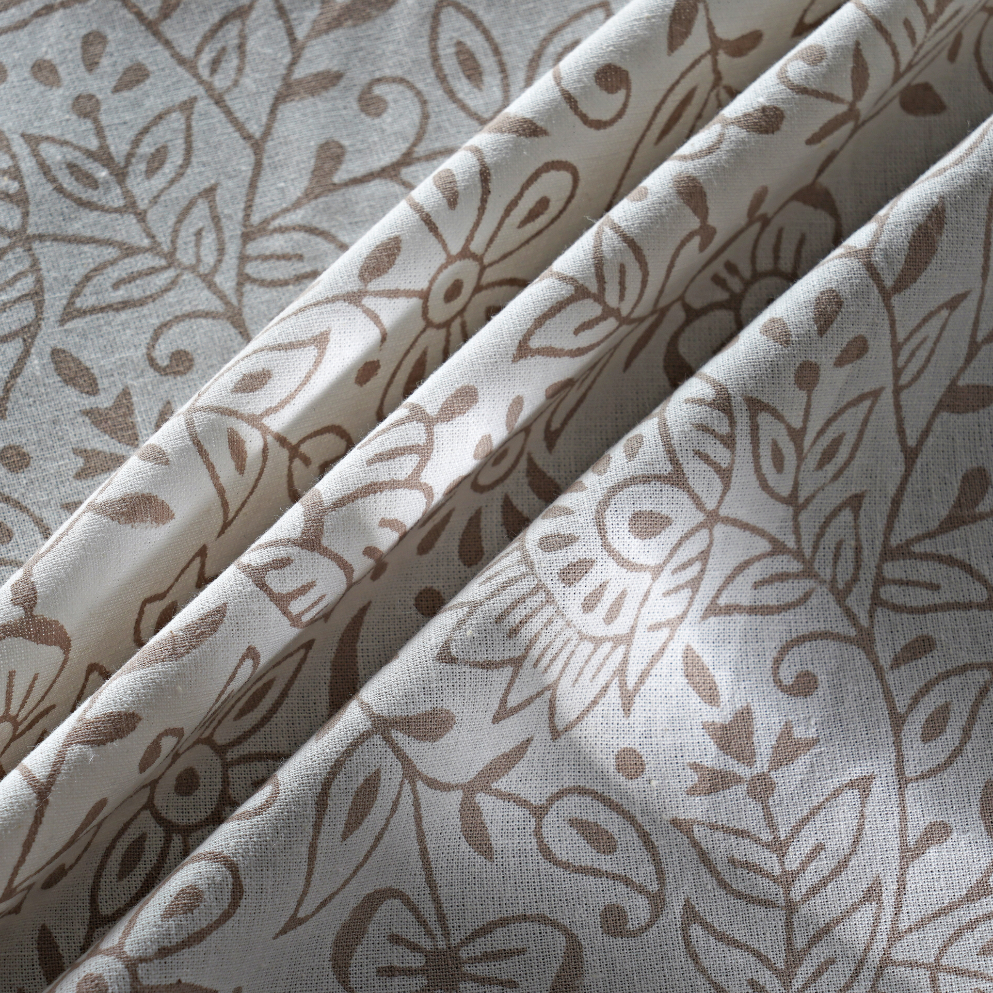 Folded fabric with brown floral pattern on a light gray background