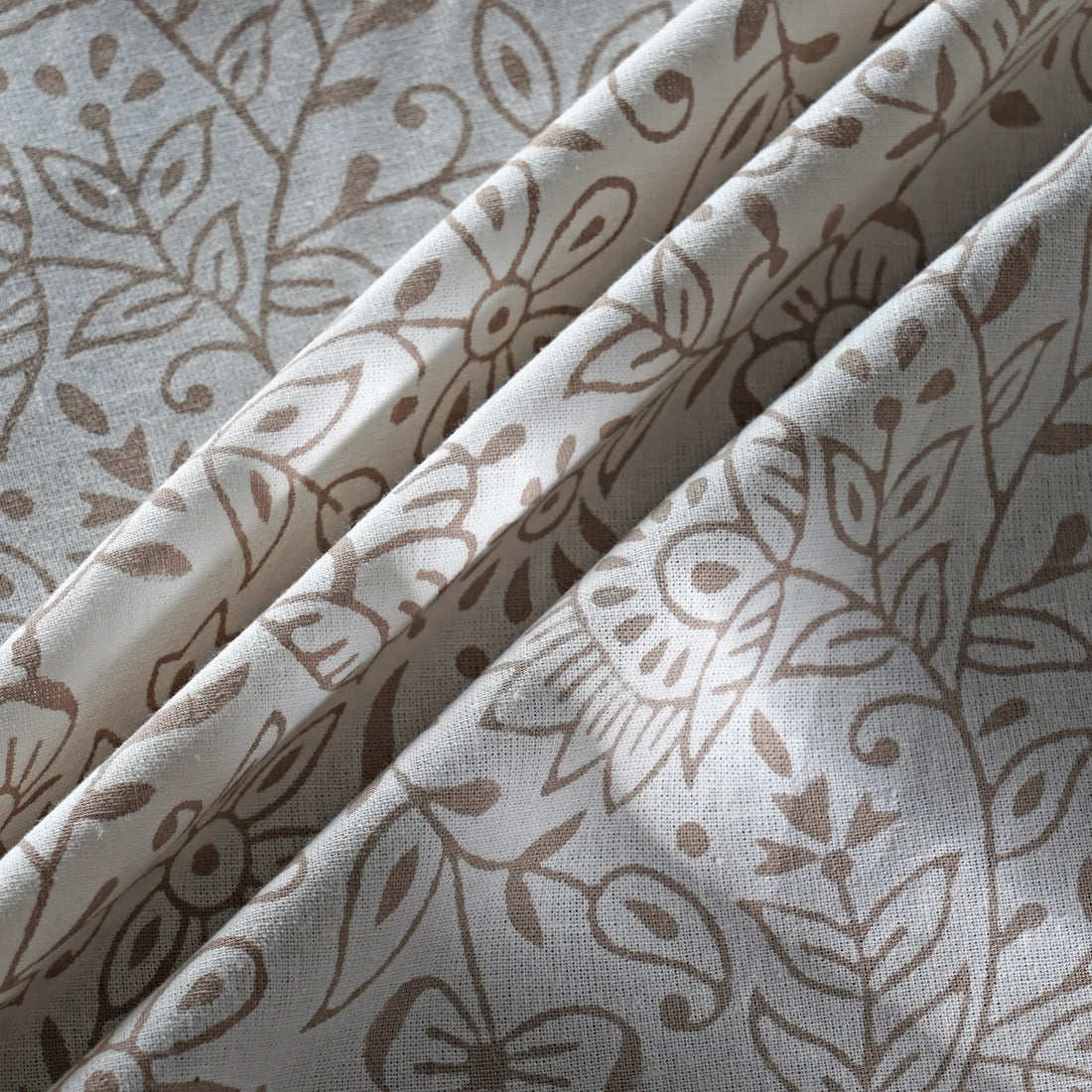 Folded fabric with brown floral pattern on a light gray background