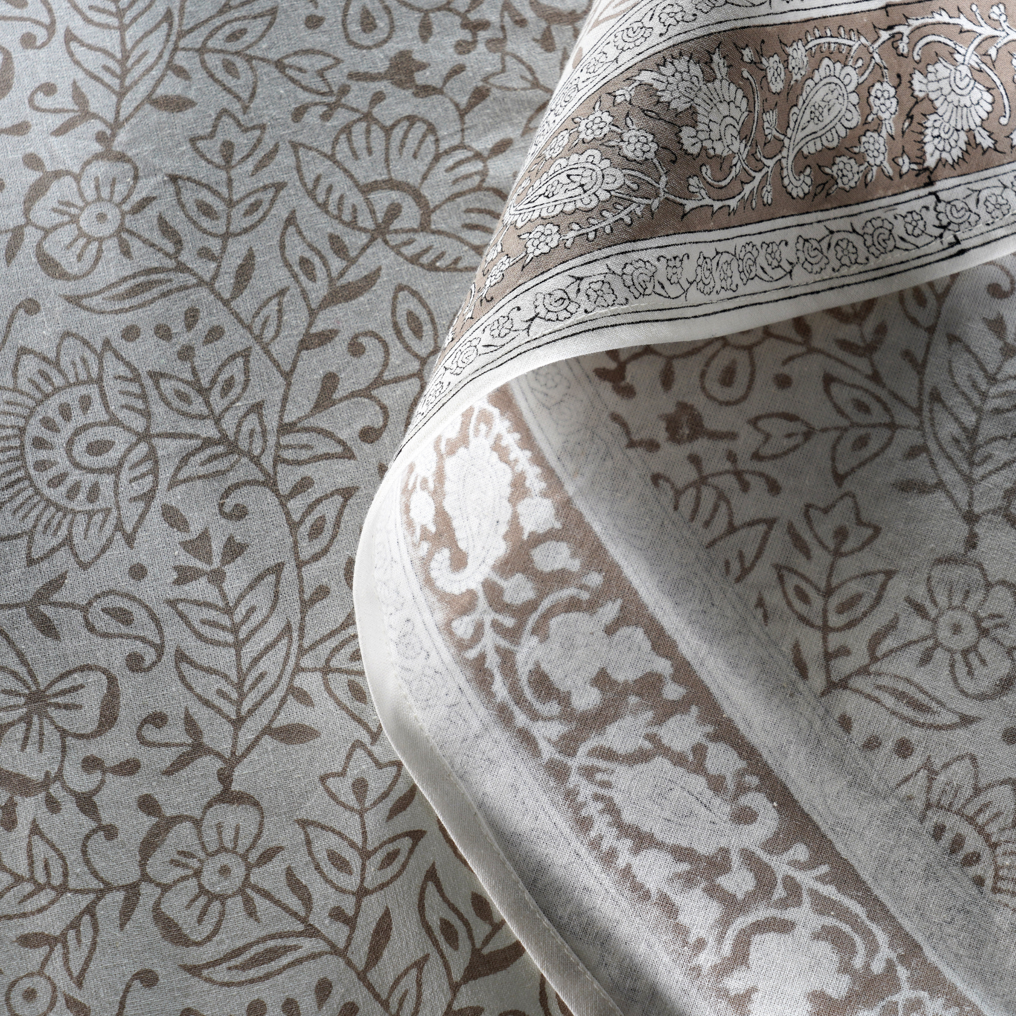 Close-up of a patterned fabric with intricate designs on a neutral background