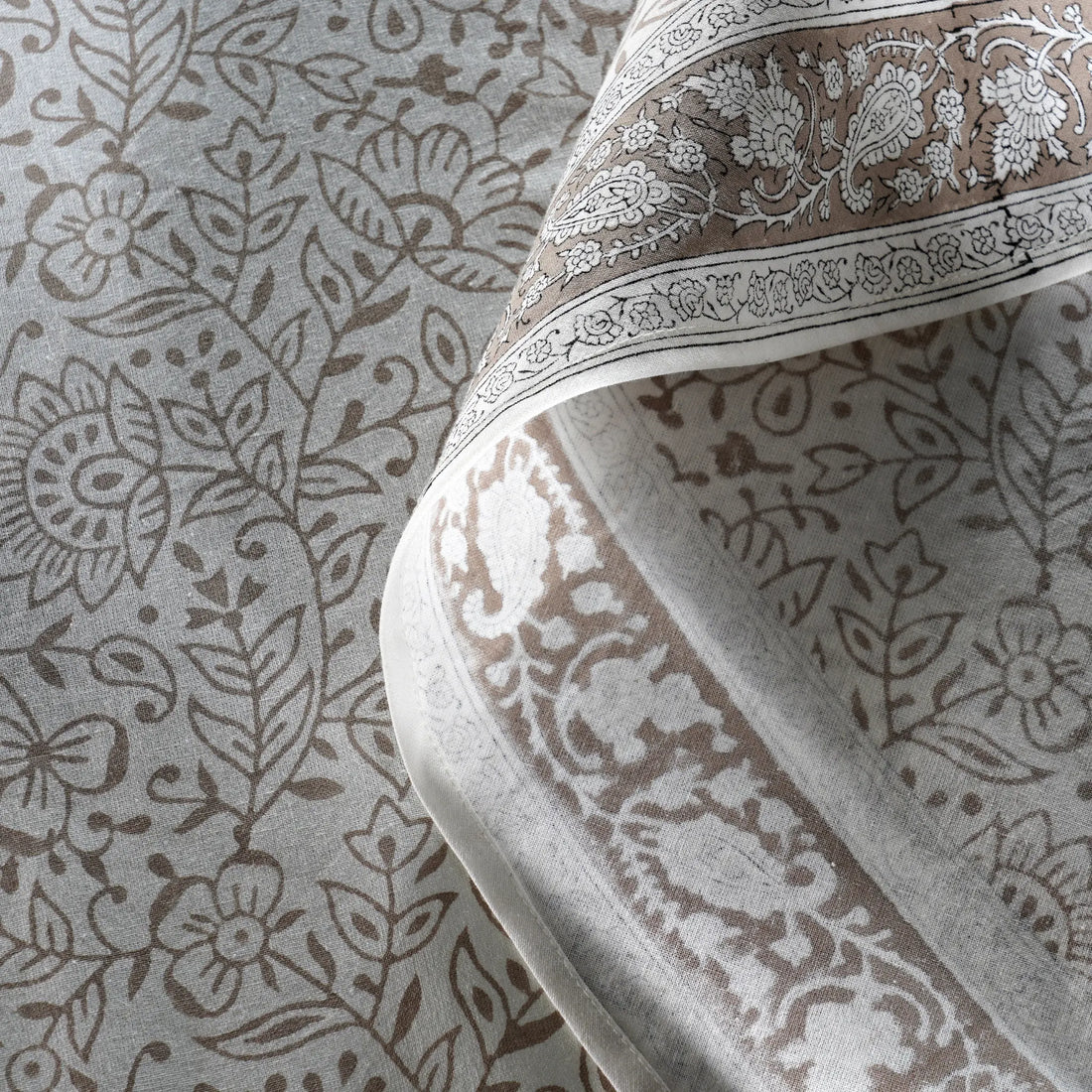 Close-up of a patterned fabric with intricate designs on a neutral background