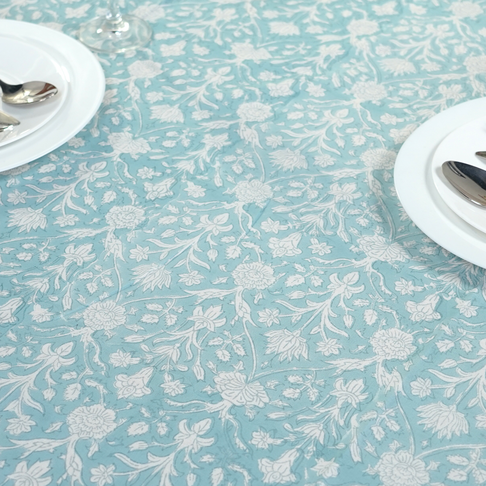 Floral patterned tablecloth on a table with white plates and silverware.