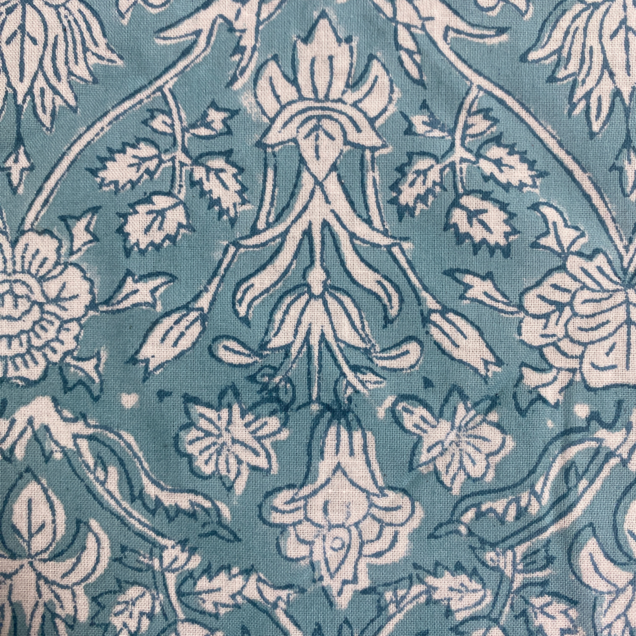 Patterned fabric with white floral and leaf design on a blue background