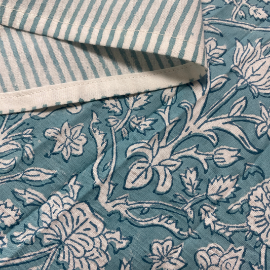 Close-up of blue floral fabric with a striped pattern underneath