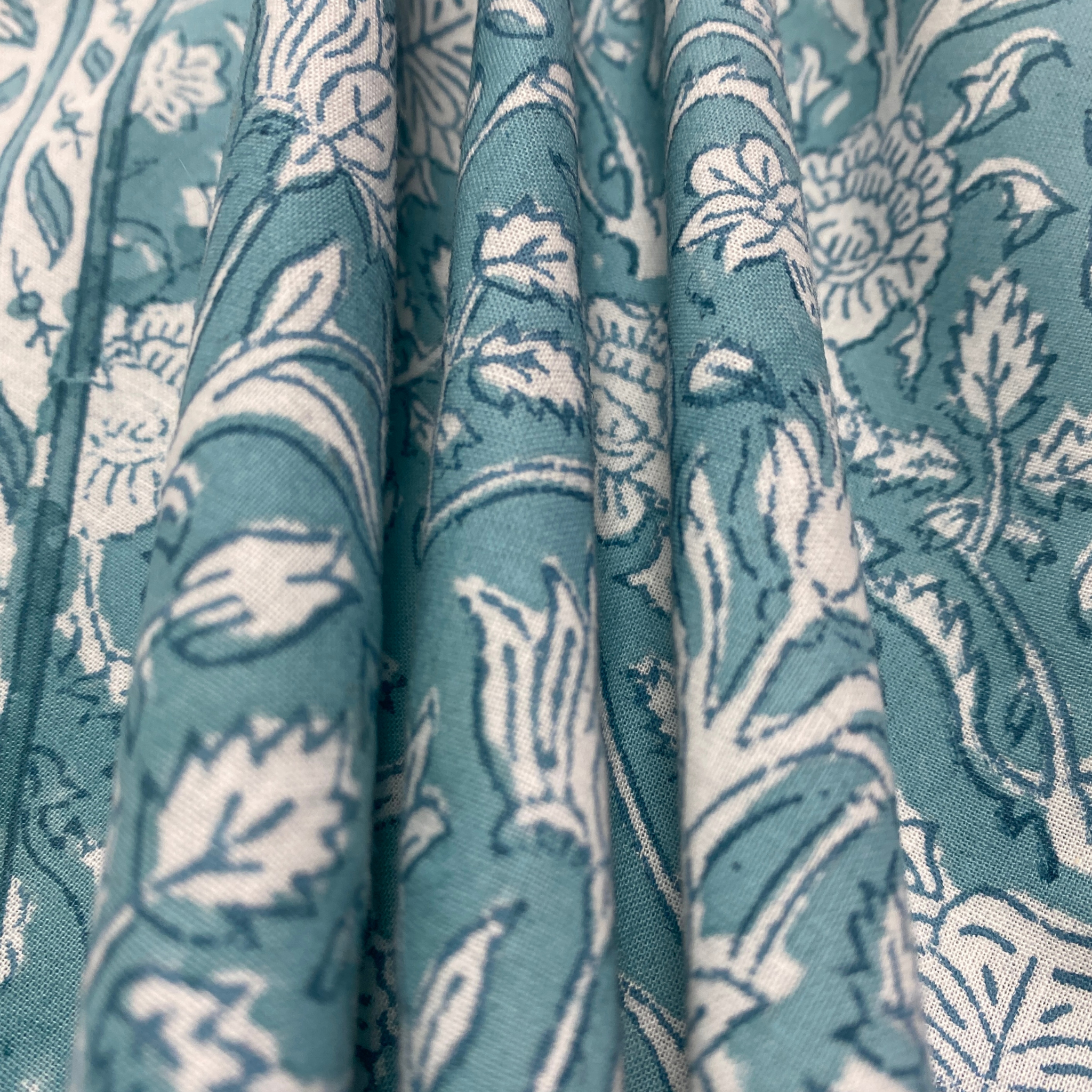 Close-up of teal fabric with white floral pattern