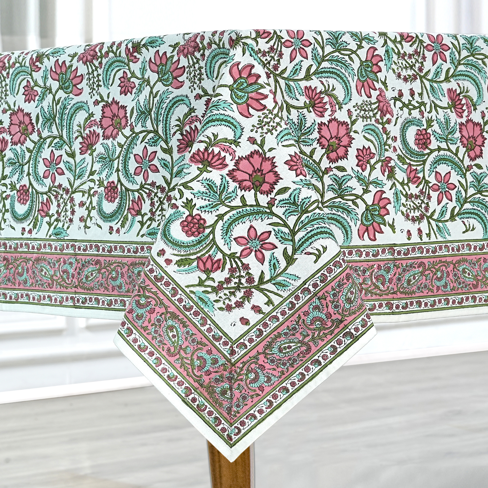 Floral patterned tablecloth on a wooden table with a white background
