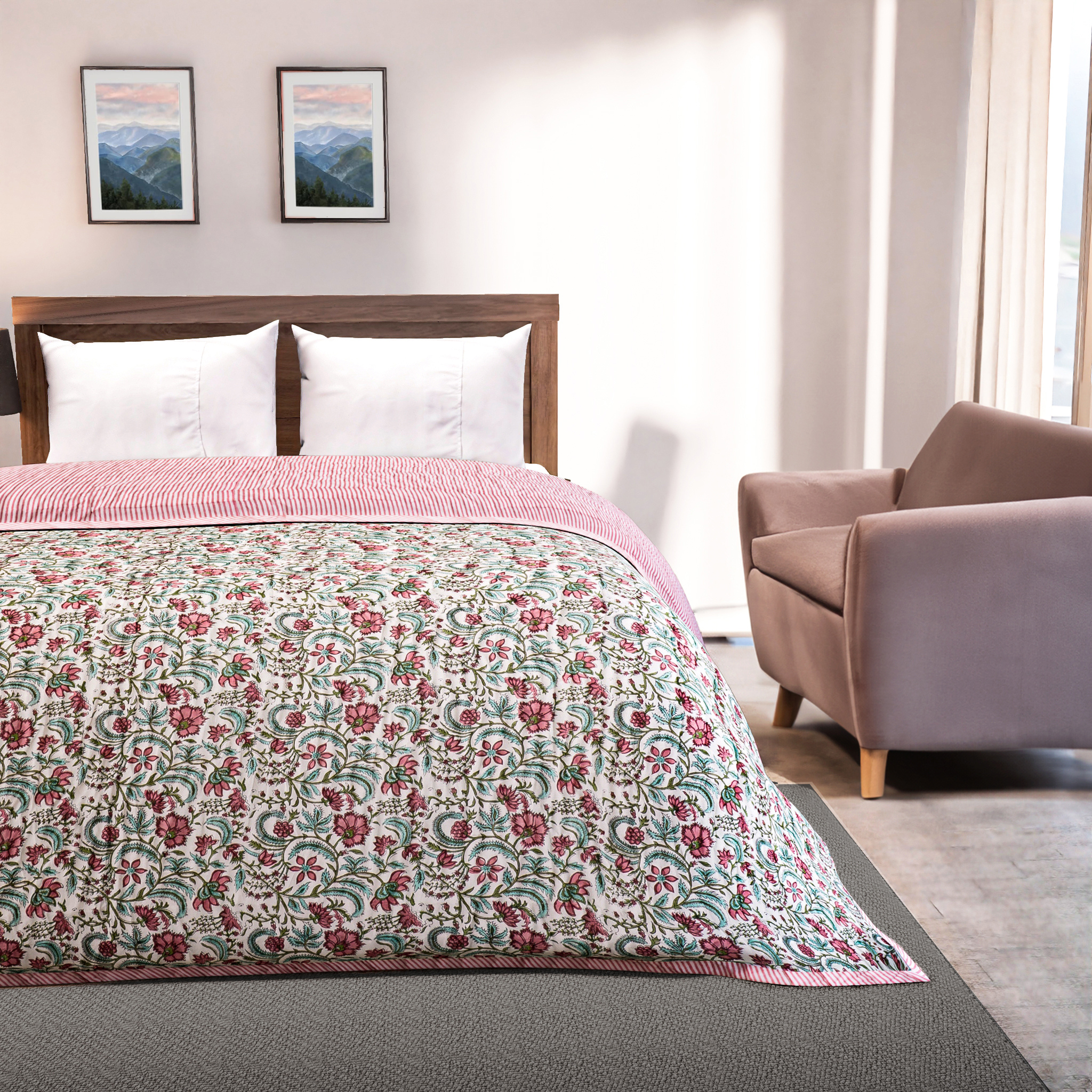 Bedroom with floral quilt on a bed, armchair, and framed pictures on the wall.