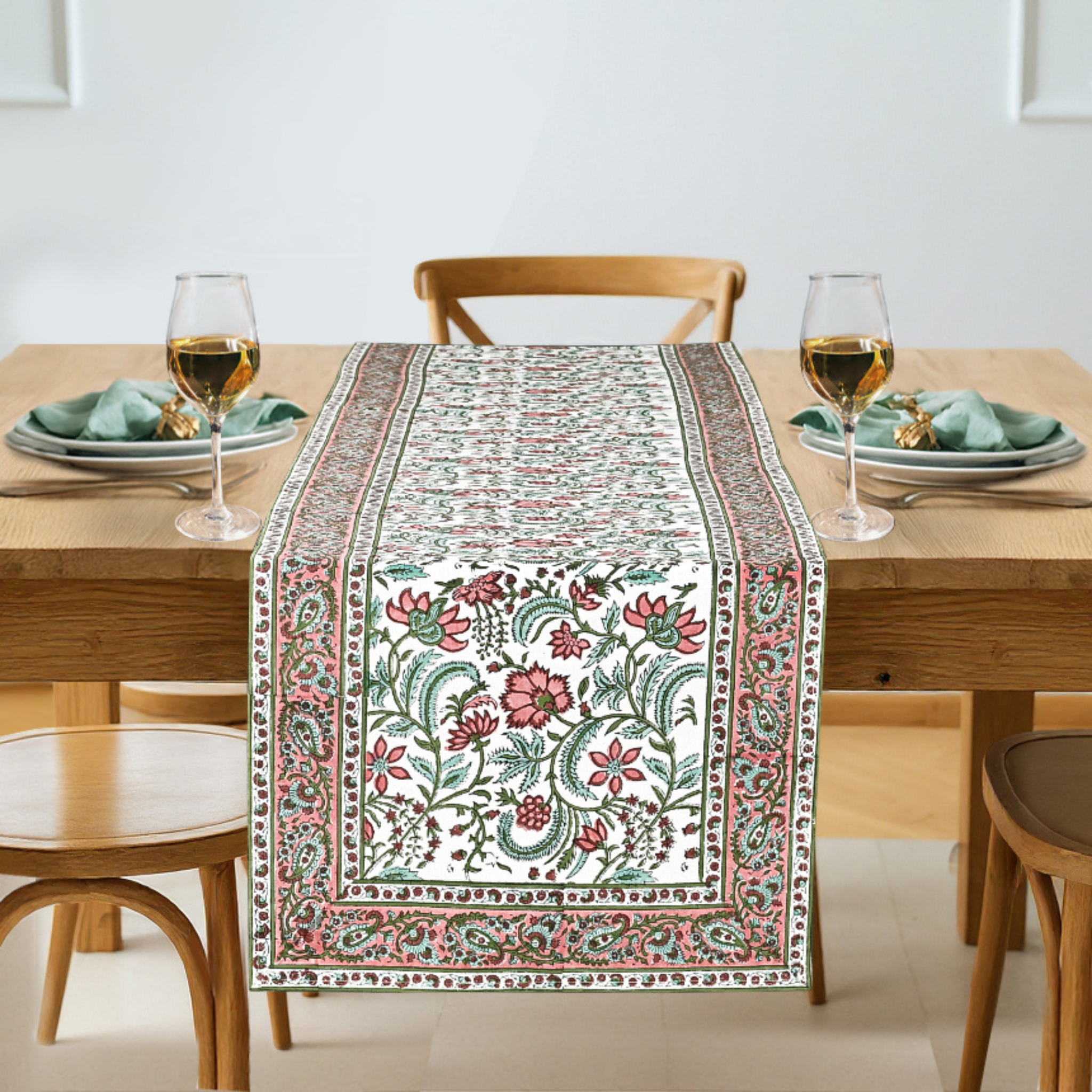 Dining table with a floral table runner, glasses, and plates on a light background