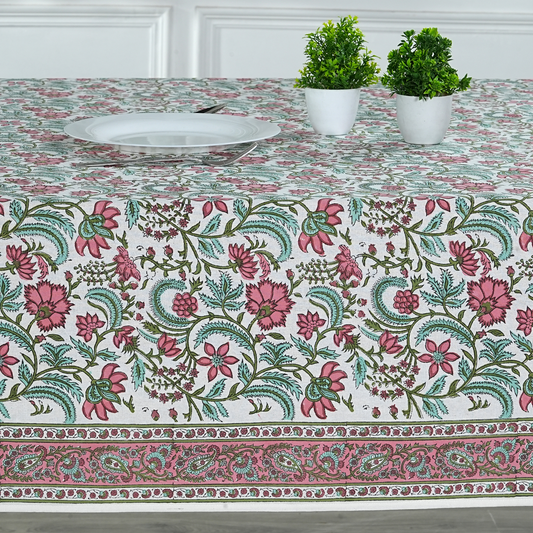 Floral patterned tablecloth on a table with two potted plants.