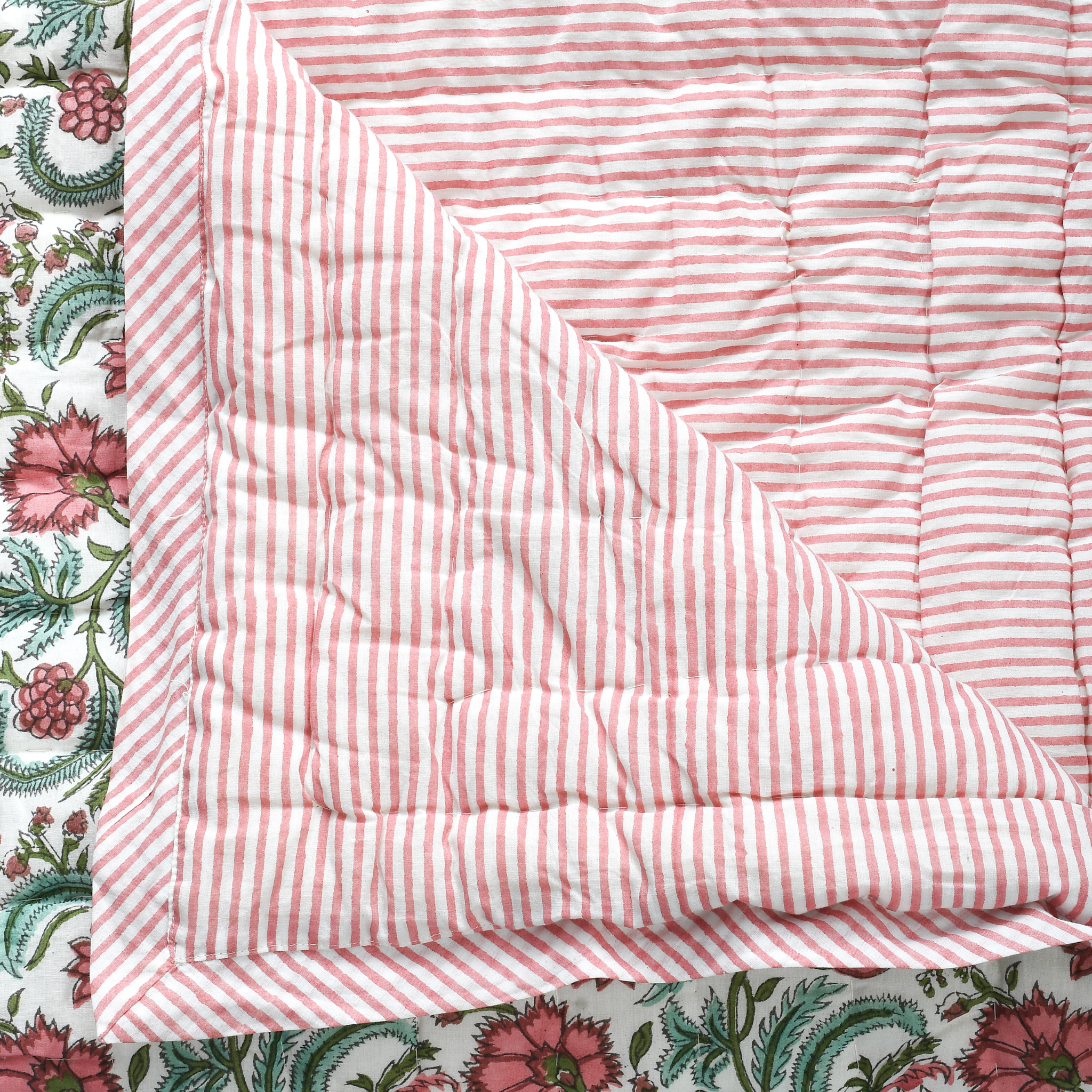 Pink and white striped quilt on a floral fabric background