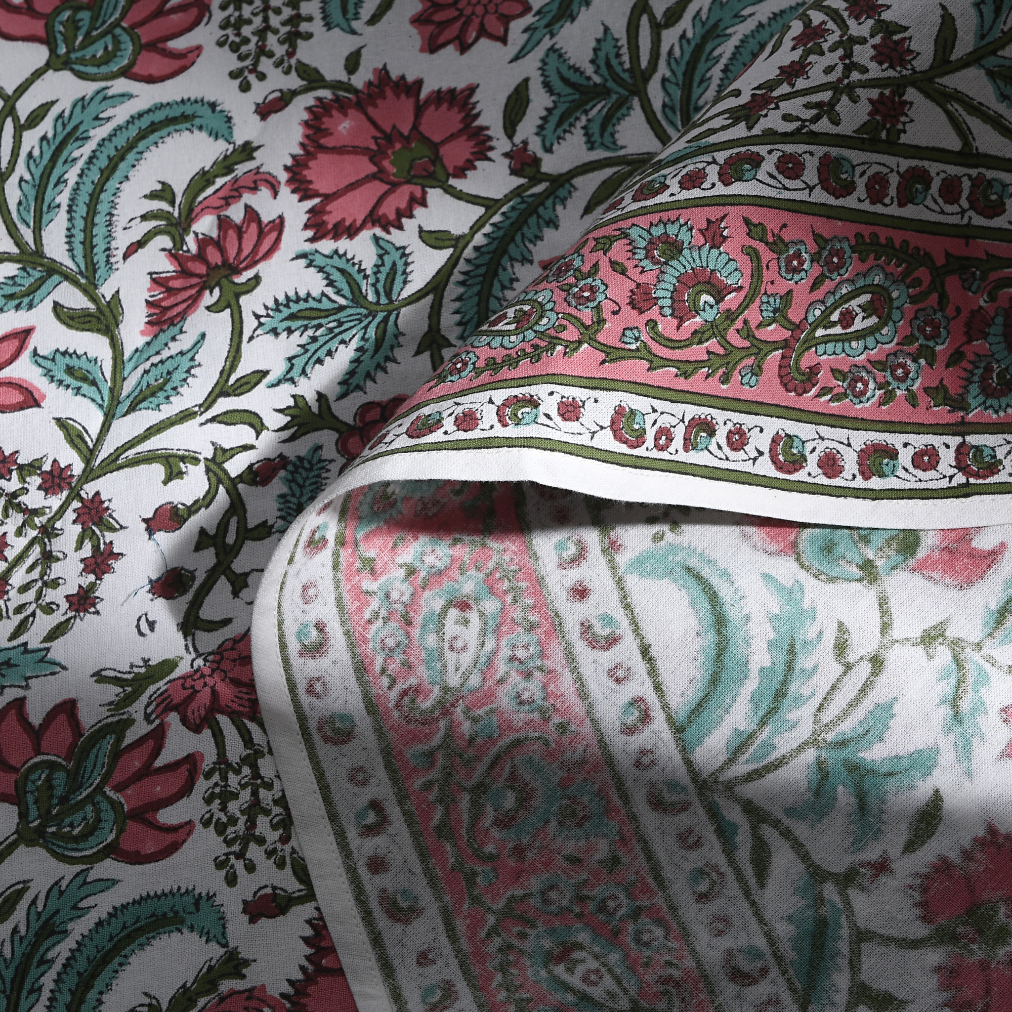 Close-up of floral and paisley patterned fabric with pink, green, and black colors.