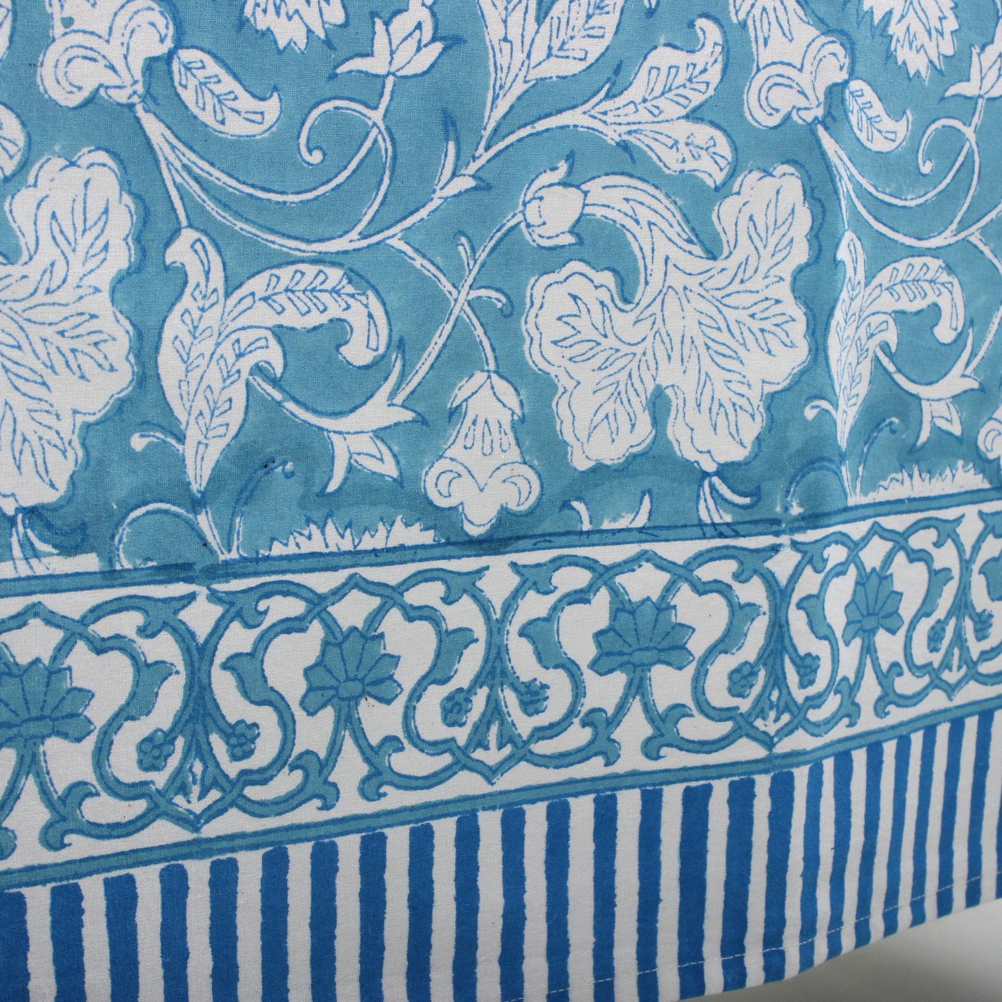 Close-up of a blue and white patterned fabric with floral and striped designs.