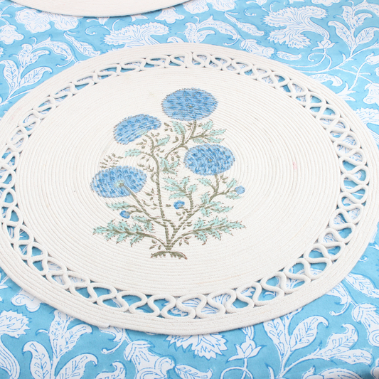 Decorative white placemat with floral design on a blue floral patterned background
