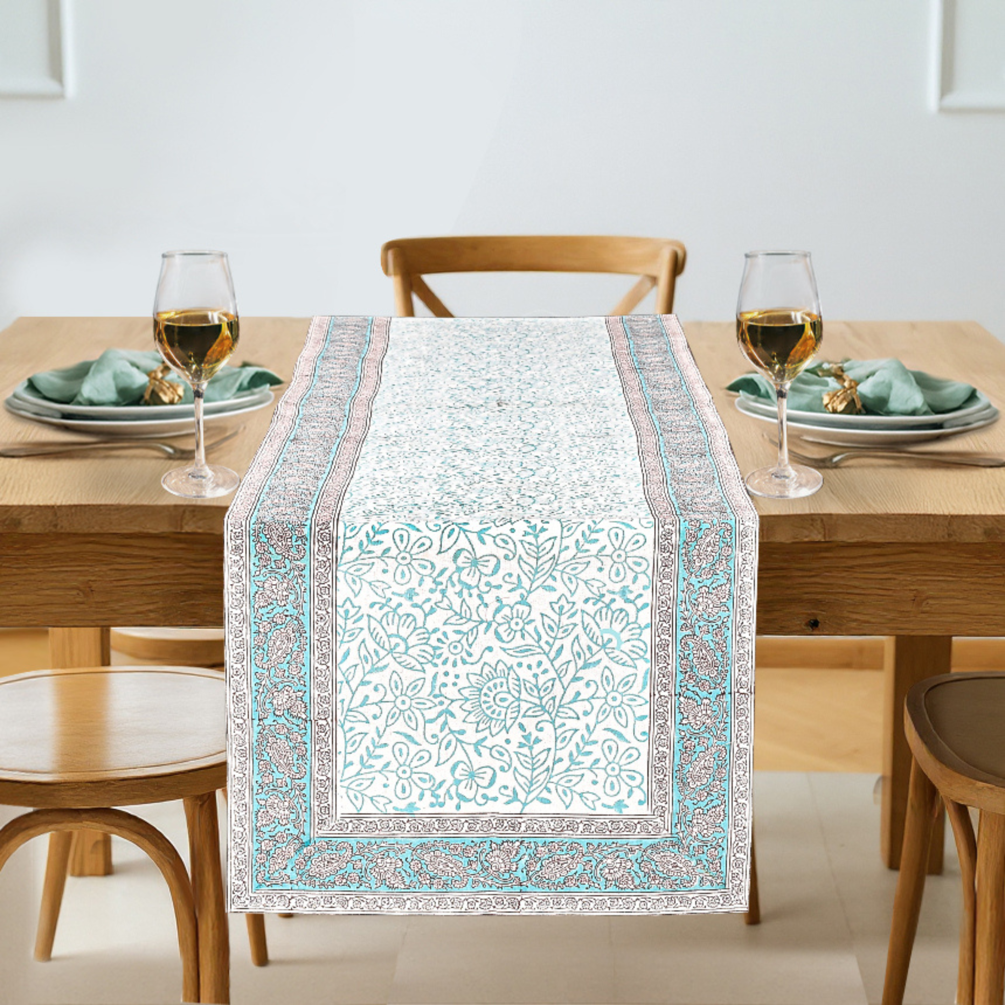 Dining table with a patterned table runner, glasses, and plates on a neutral background