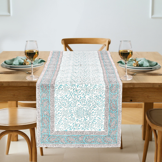 Dining table with a patterned table runner, glasses, and plates on a neutral background