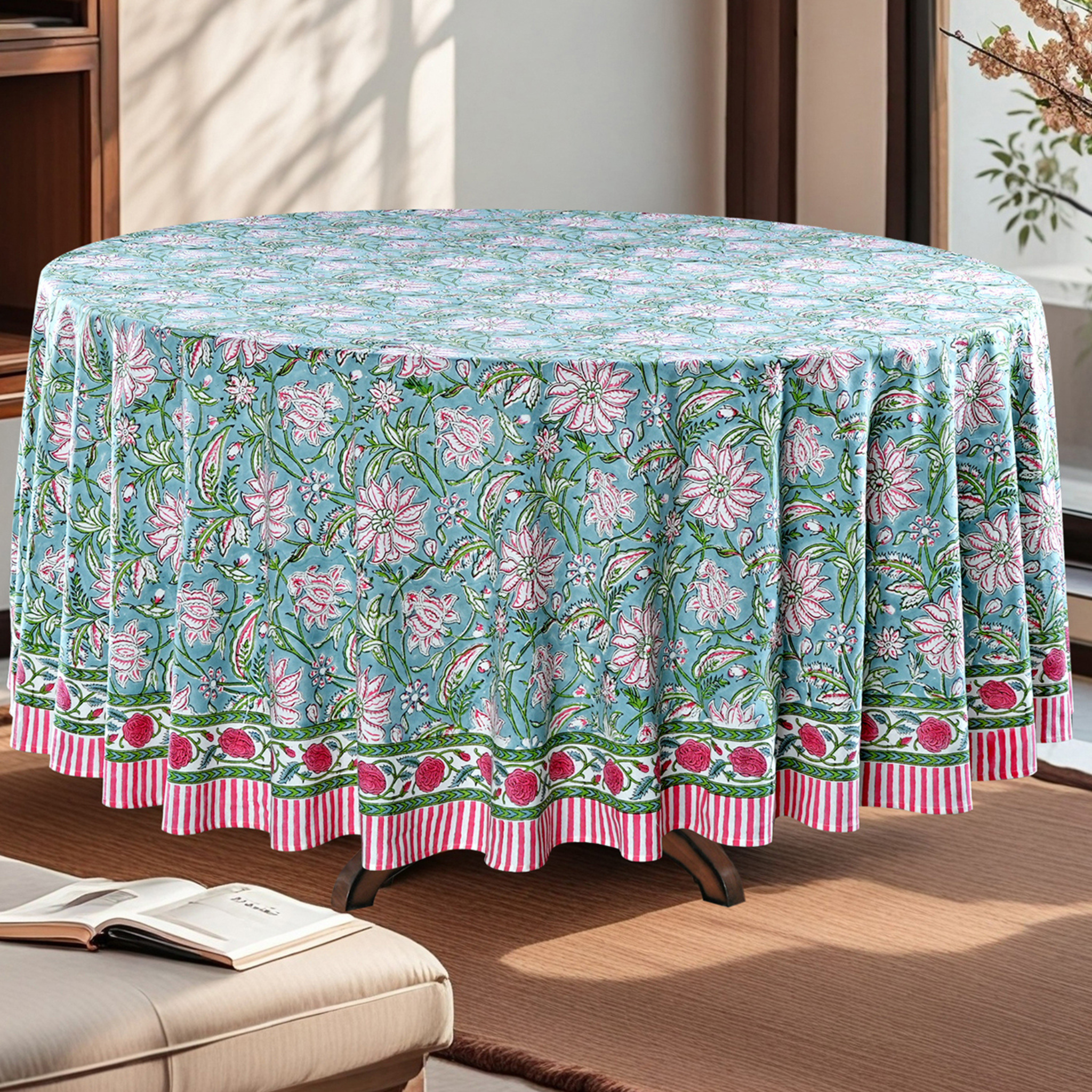 Floral patterned tablecloth on a round table in a room with a couch and open book.