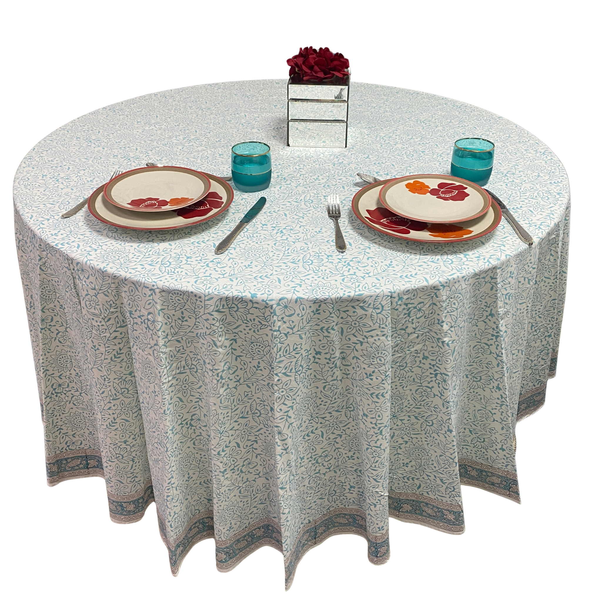 Round table set with place settings, glasses, and a floral centerpiece on a white background