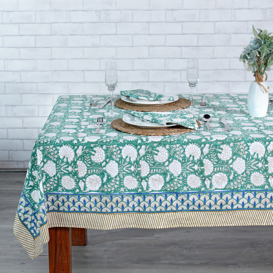 Tablecloth with floral pattern on a wooden table against a white brick wall.