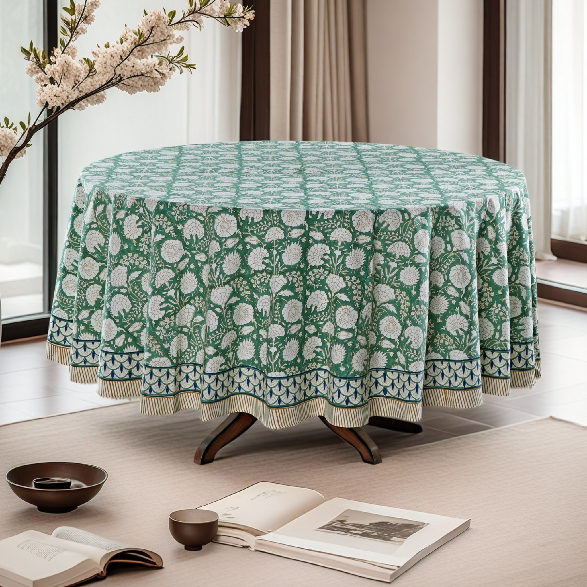 Round table with a green floral patterned tablecloth in a bright room.