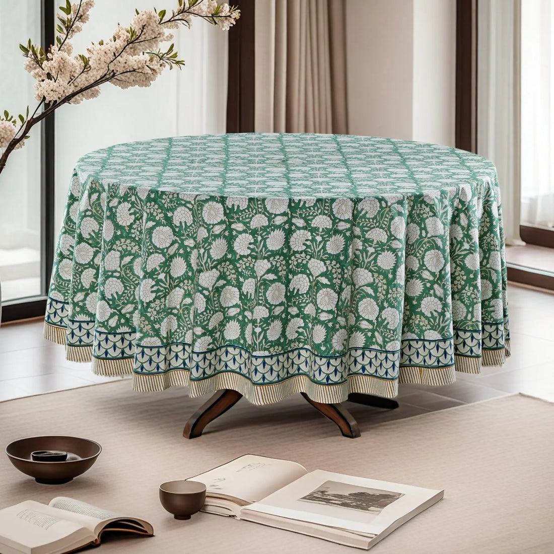 Round table with a green floral patterned tablecloth in a bright room.