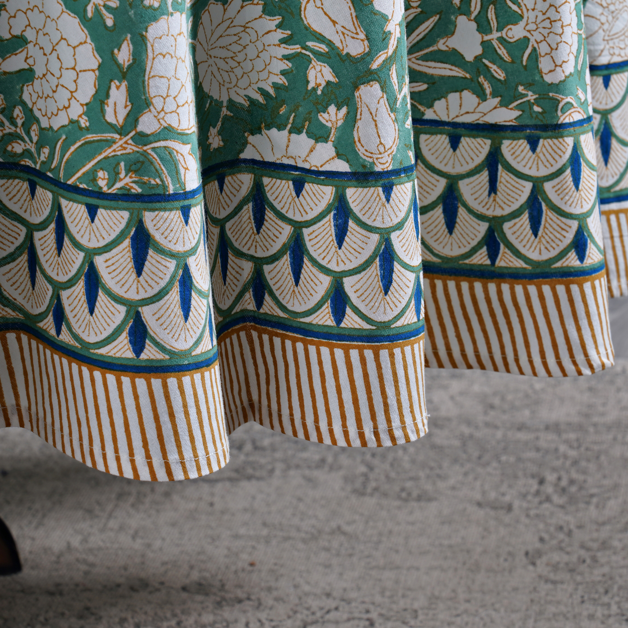 Close-up of patterned fabric with green, white, and blue design on a textured surface.