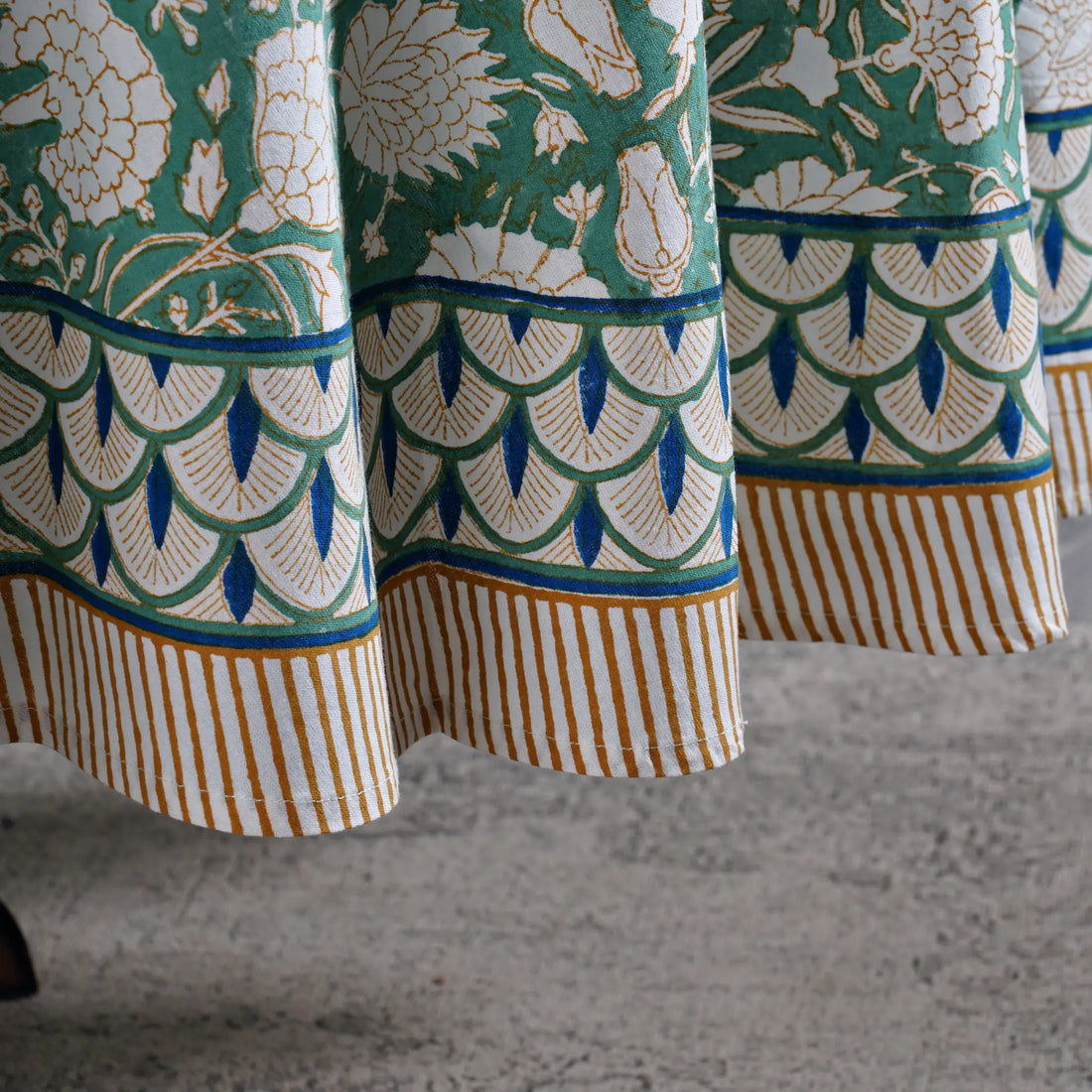 Close-up of patterned fabric with green, white, and blue design on a textured surface.