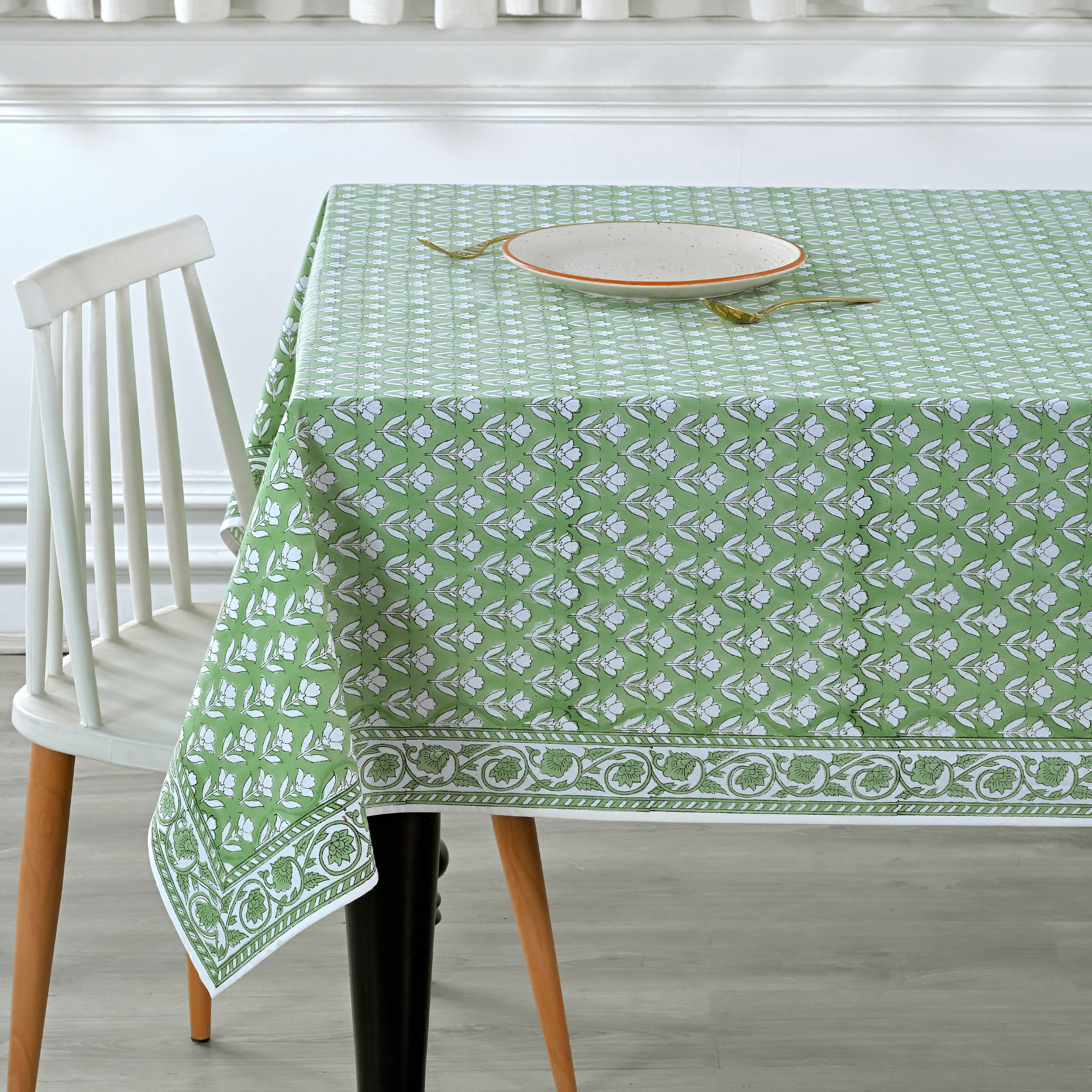 Green patterned tablecloth on a dining table with a white chair.