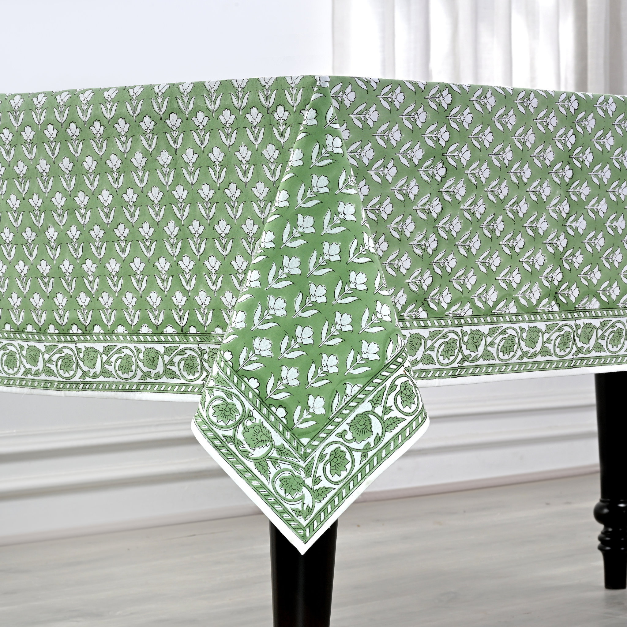 Green and white patterned tablecloth on a table with a white curtain background