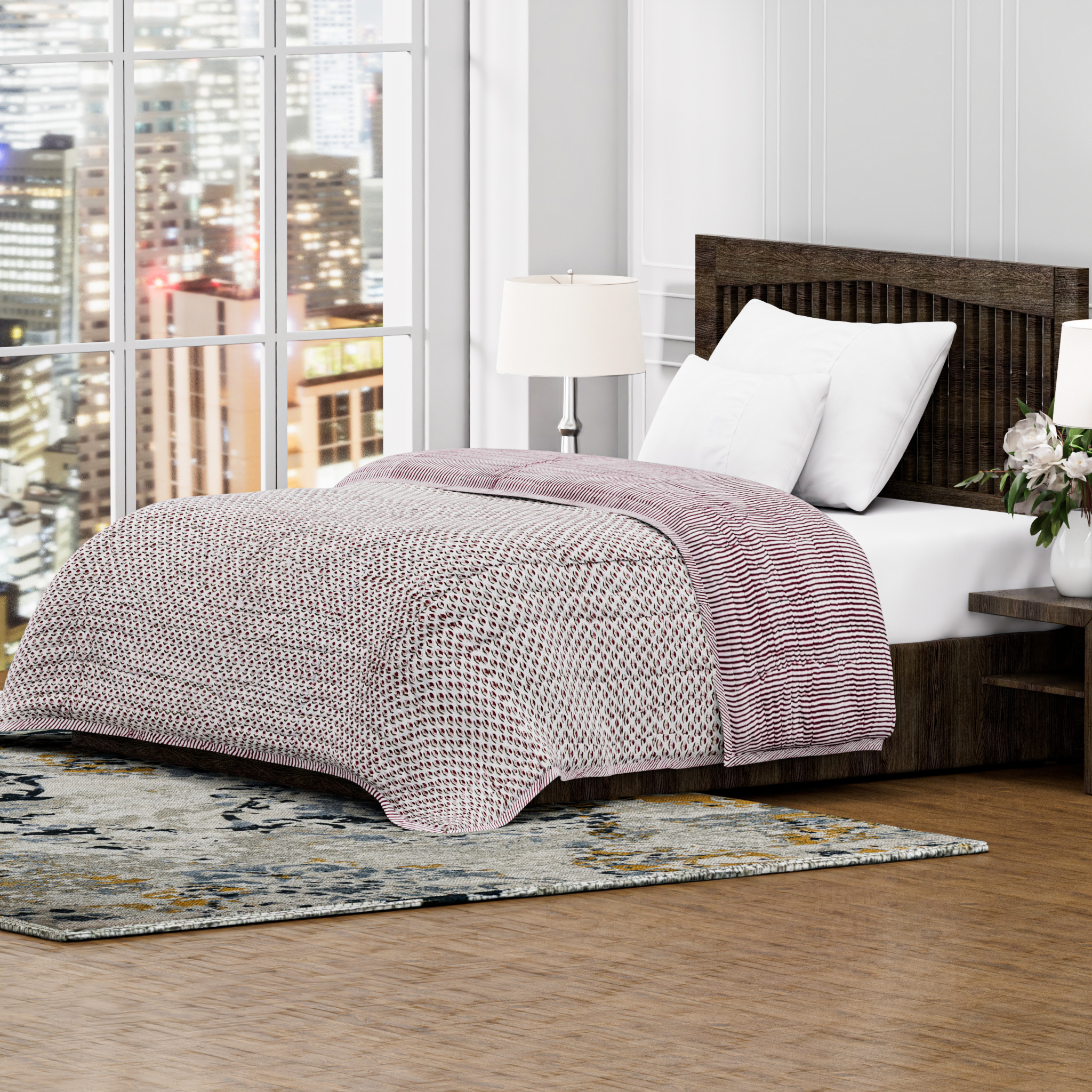 Bedroom with a bed featuring a purple quilt, white pillows, and wooden headboard. Cityscape visible through large windows.