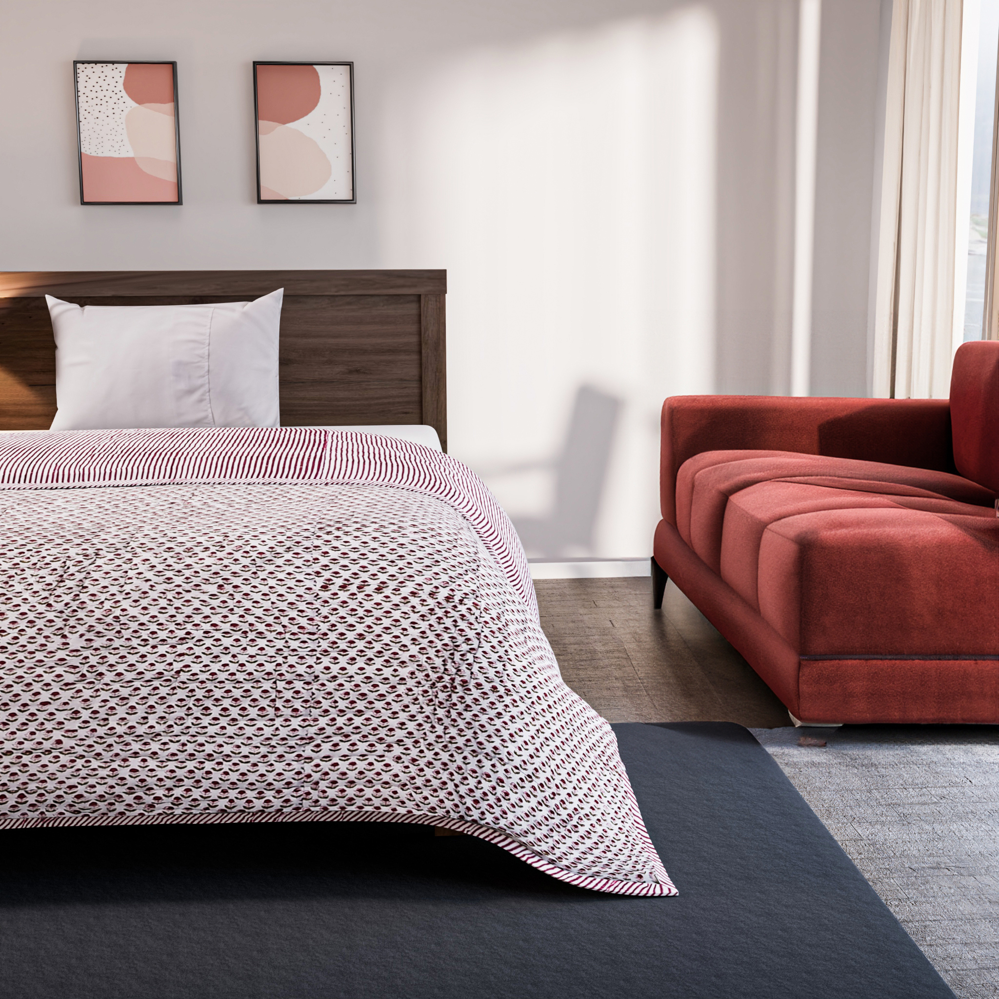Bedroom with a bed covered in a patterned comforter and a red sofa.