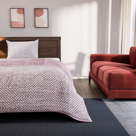Bedroom with a bed covered in a patterned comforter and a red sofa.