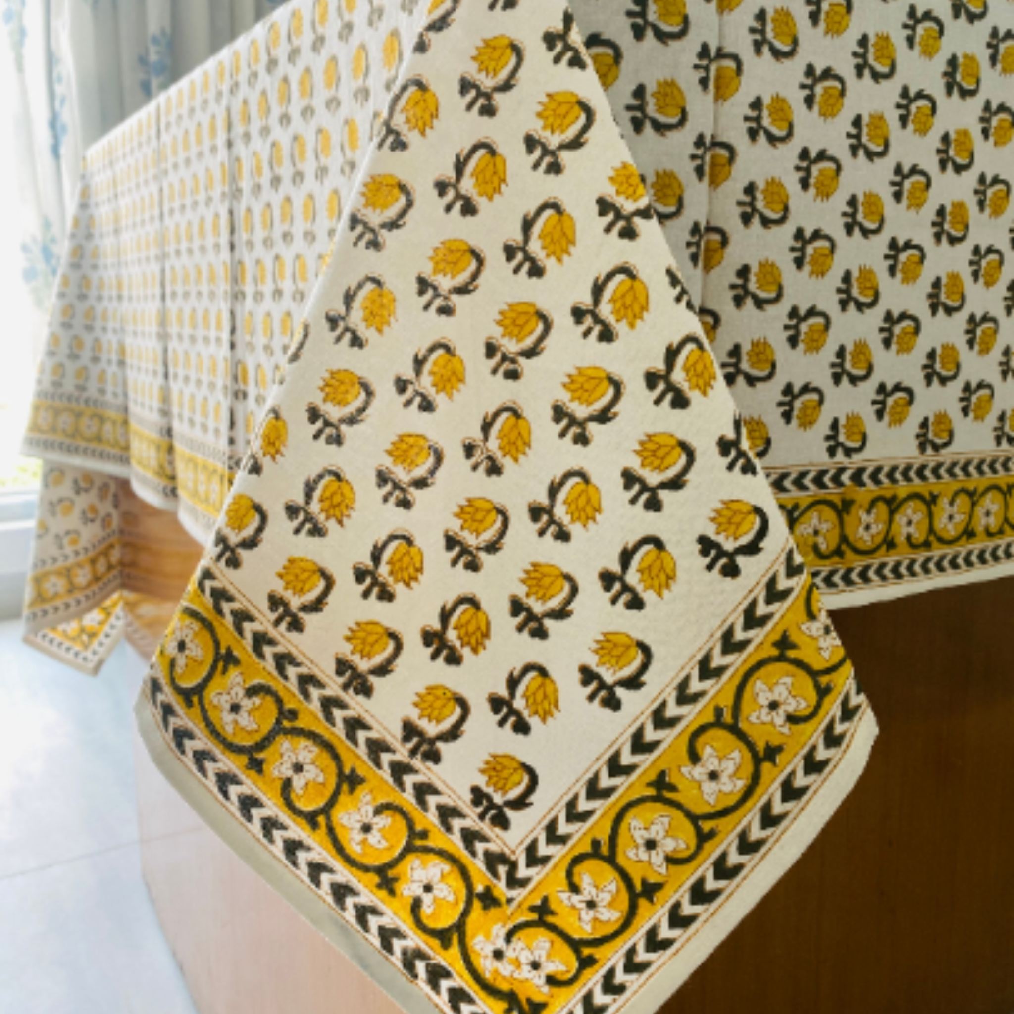 Decorative tablecloth with yellow and black floral pattern on a white surface