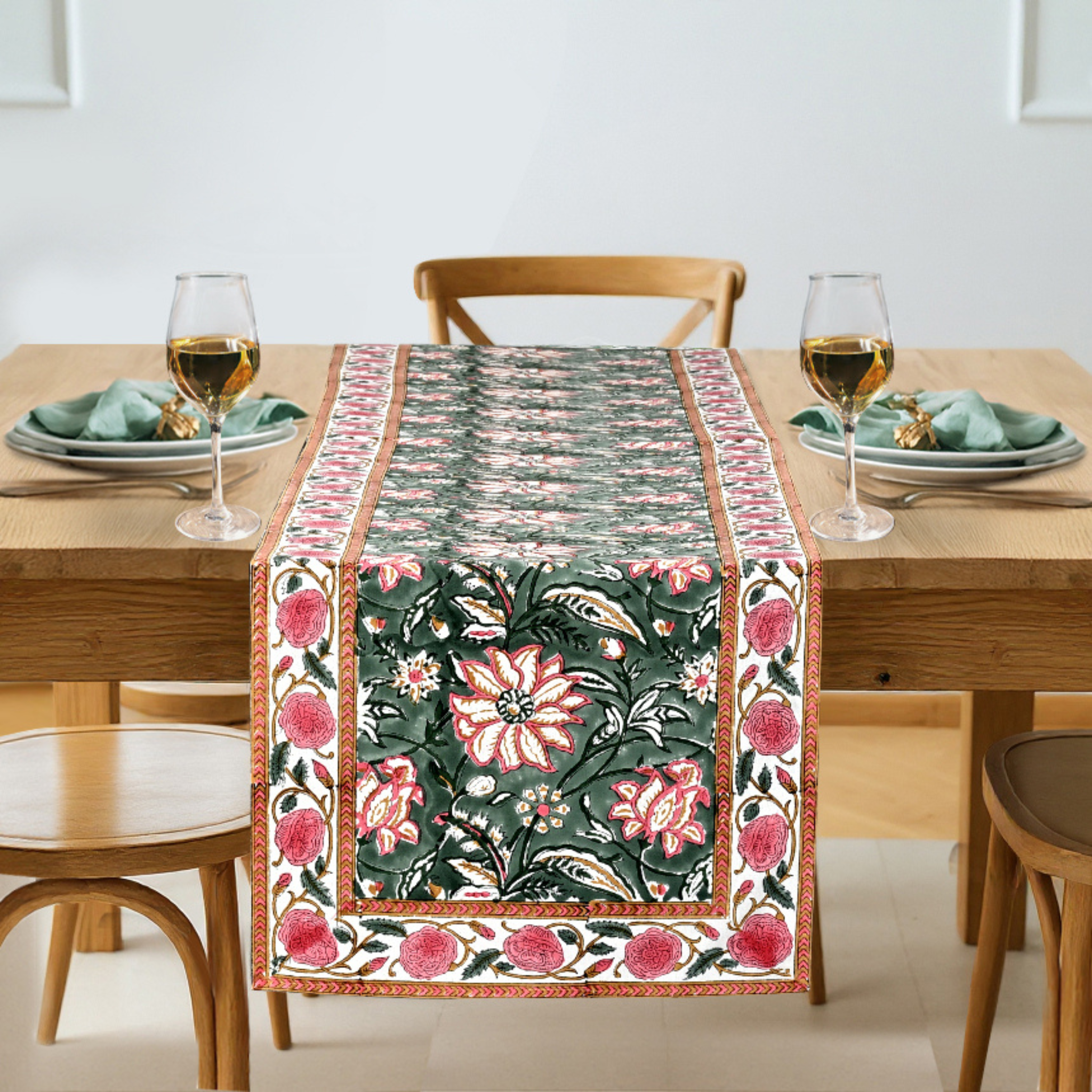 Dining table with a floral table runner, glasses, and plates.