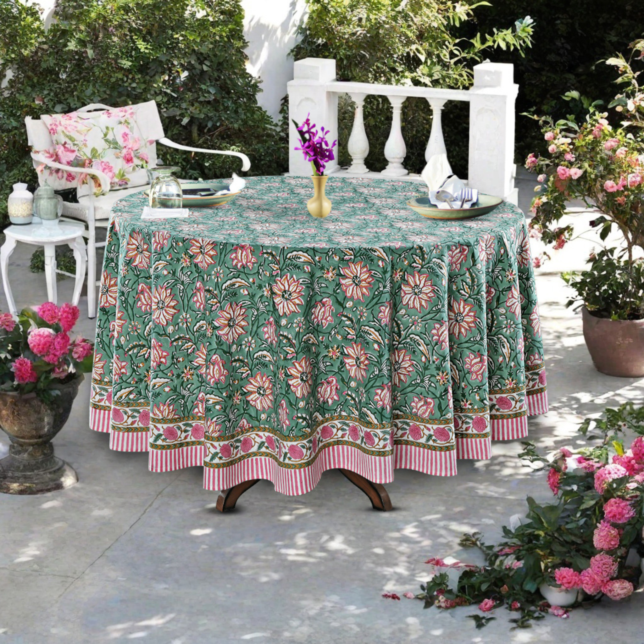 Outdoor table setting with a floral tablecloth, chairs, and decorative elements.