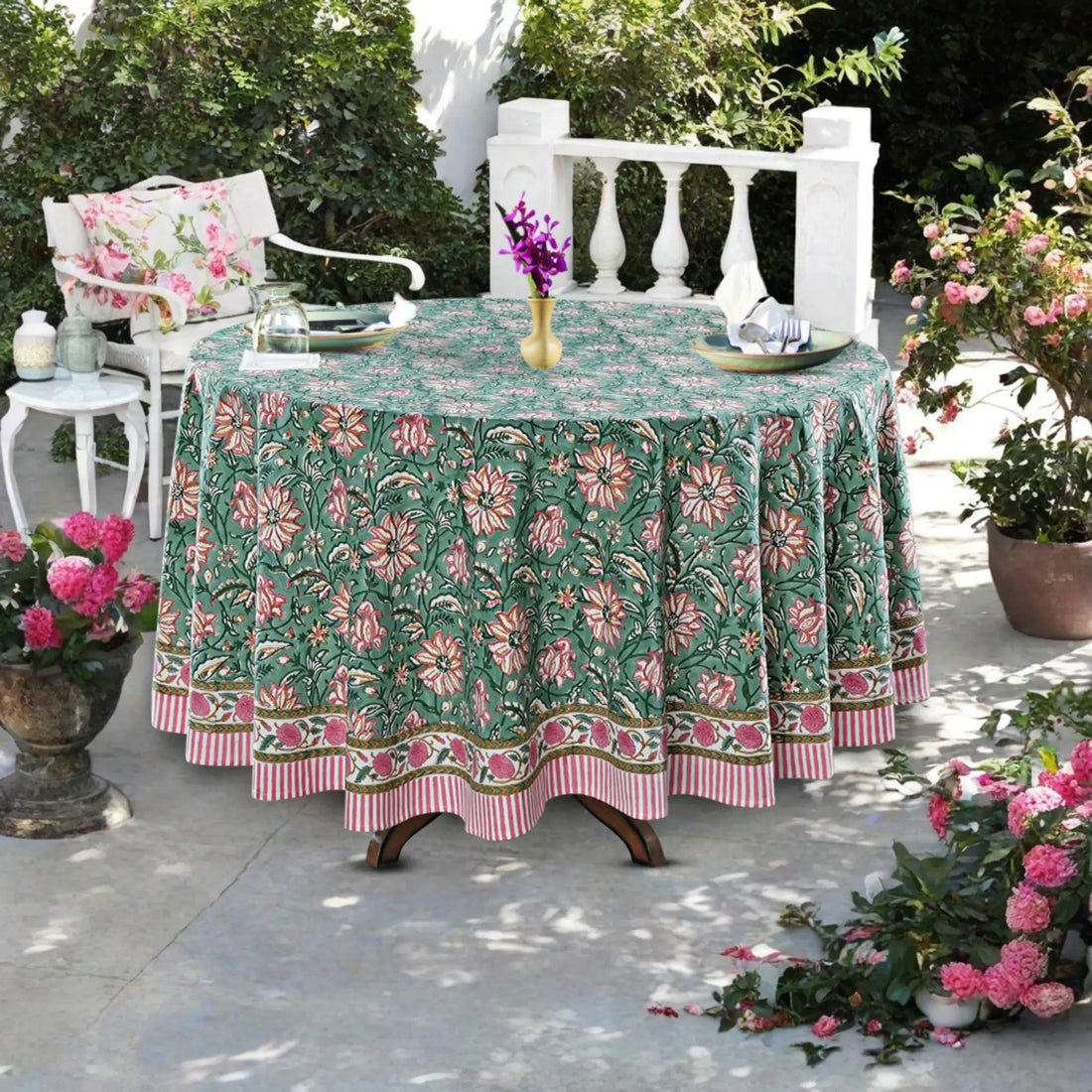 Outdoor table setting with a floral tablecloth, chairs, and decorative elements.