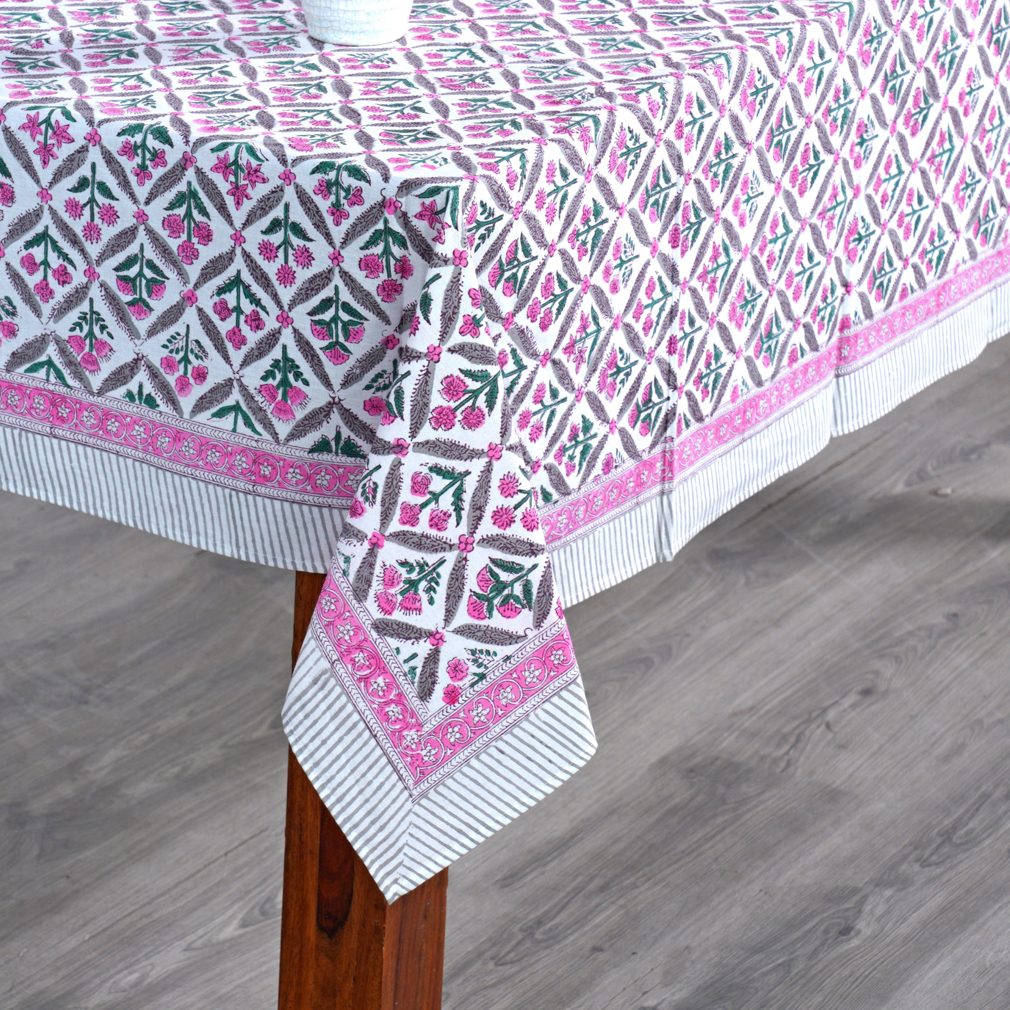 Patterned tablecloth on a wooden table with a gray floor background