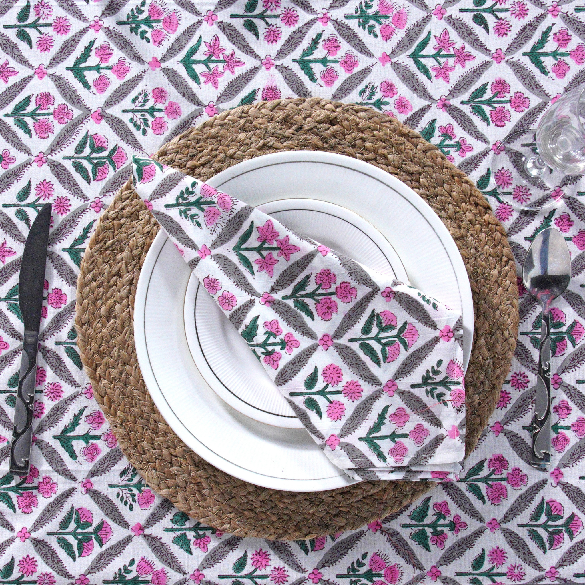 Table setting with a floral-patterned napkin on a decorative tablecloth.
