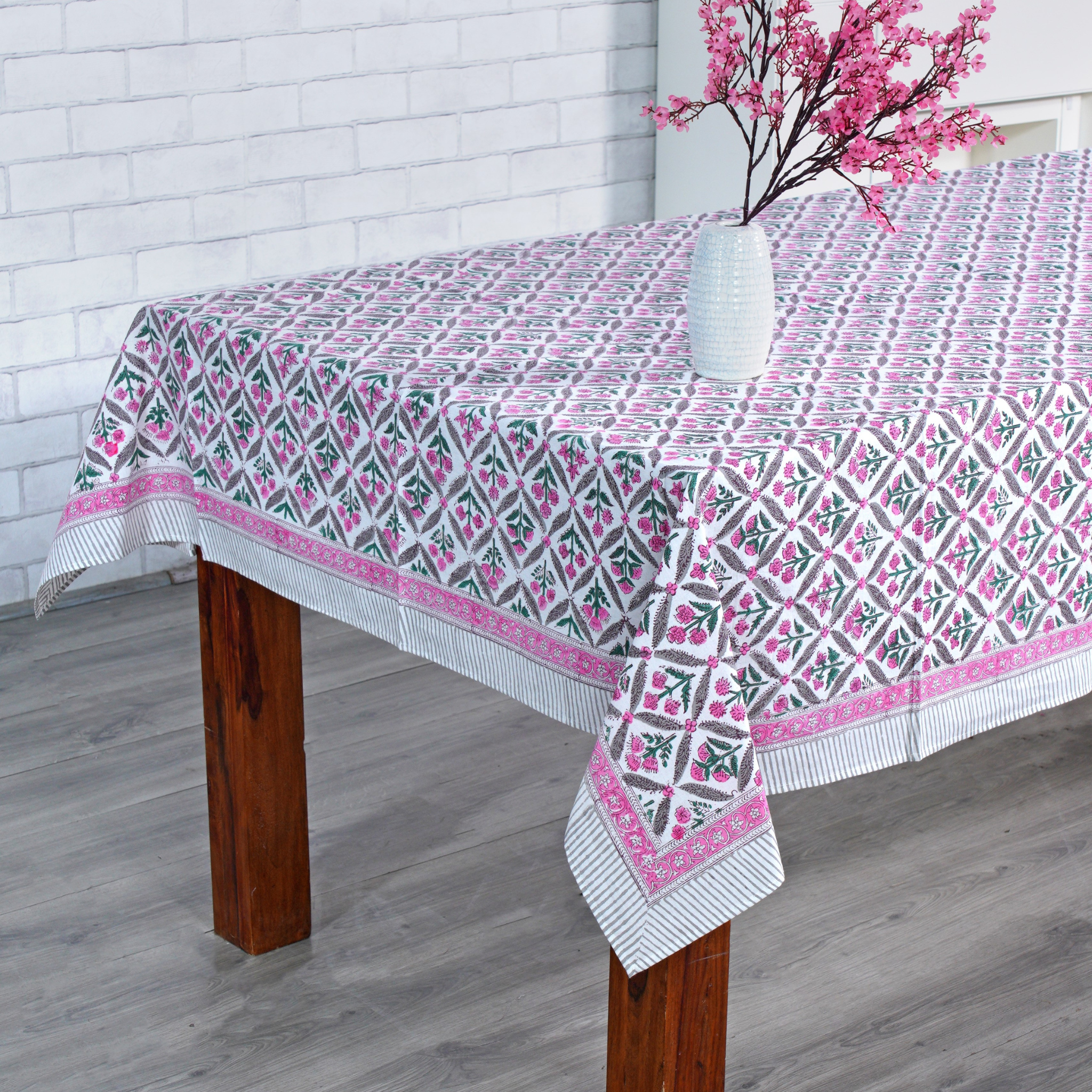 Tablecloth with geometric pattern on a wooden table against a white brick wall.